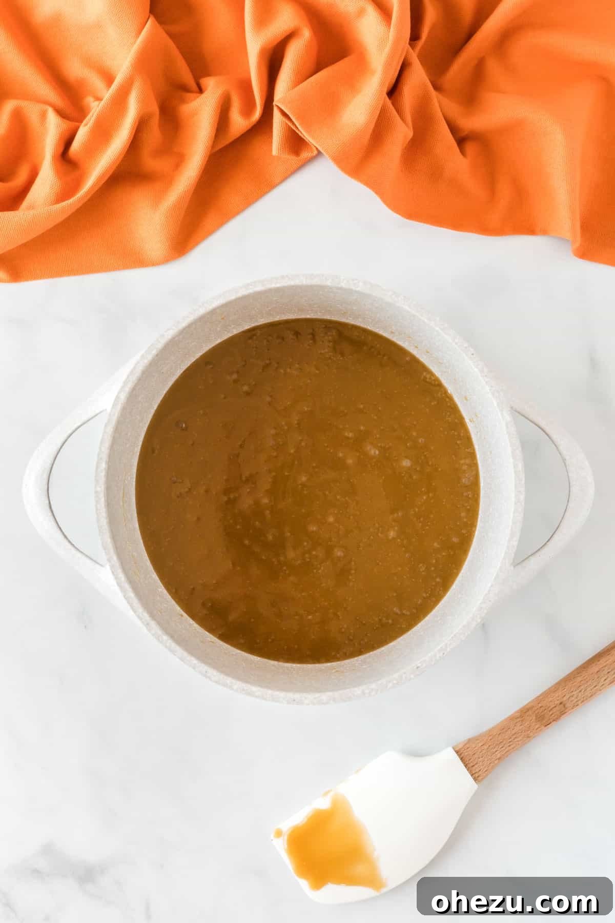 The butter and brown sugar mixture has transformed into a thick, golden toffee after boiling, ready for the next step.