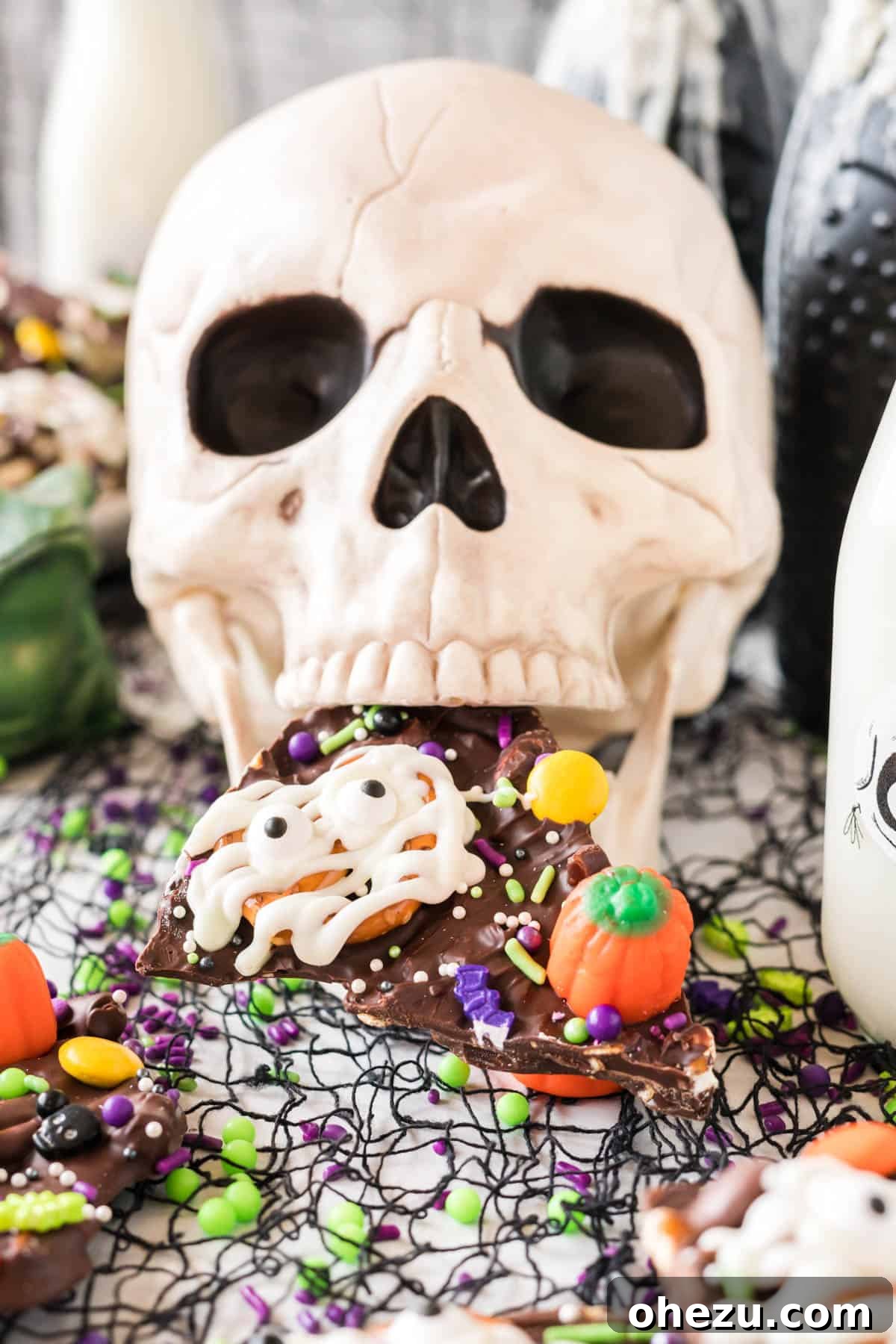 A skull decoration with a piece of Halloween bark in its mouth, adding to the spooky theme