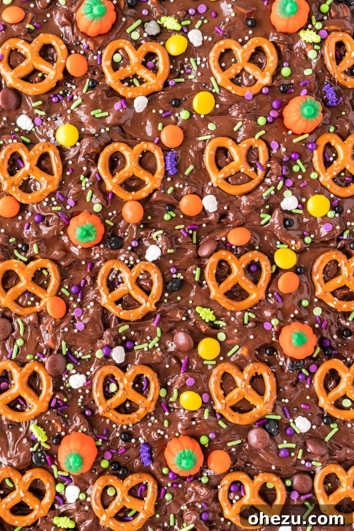 Close-up of Halloween bark decorated with candy pumpkins, sprinkles, and Reese's pieces