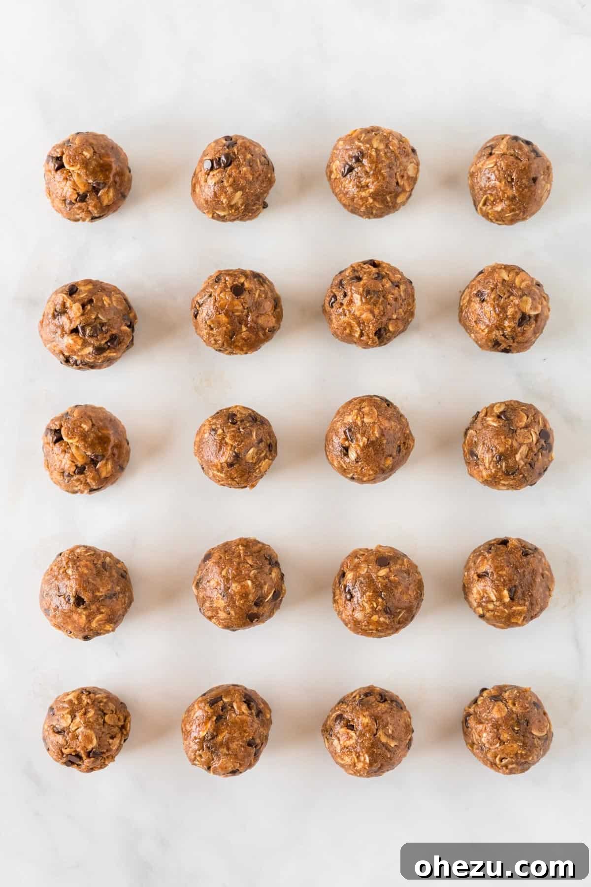 Rows of perfectly formed pumpkin protein balls arranged on a baking sheet, showcasing their appetizing appearance and readiness for consumption.