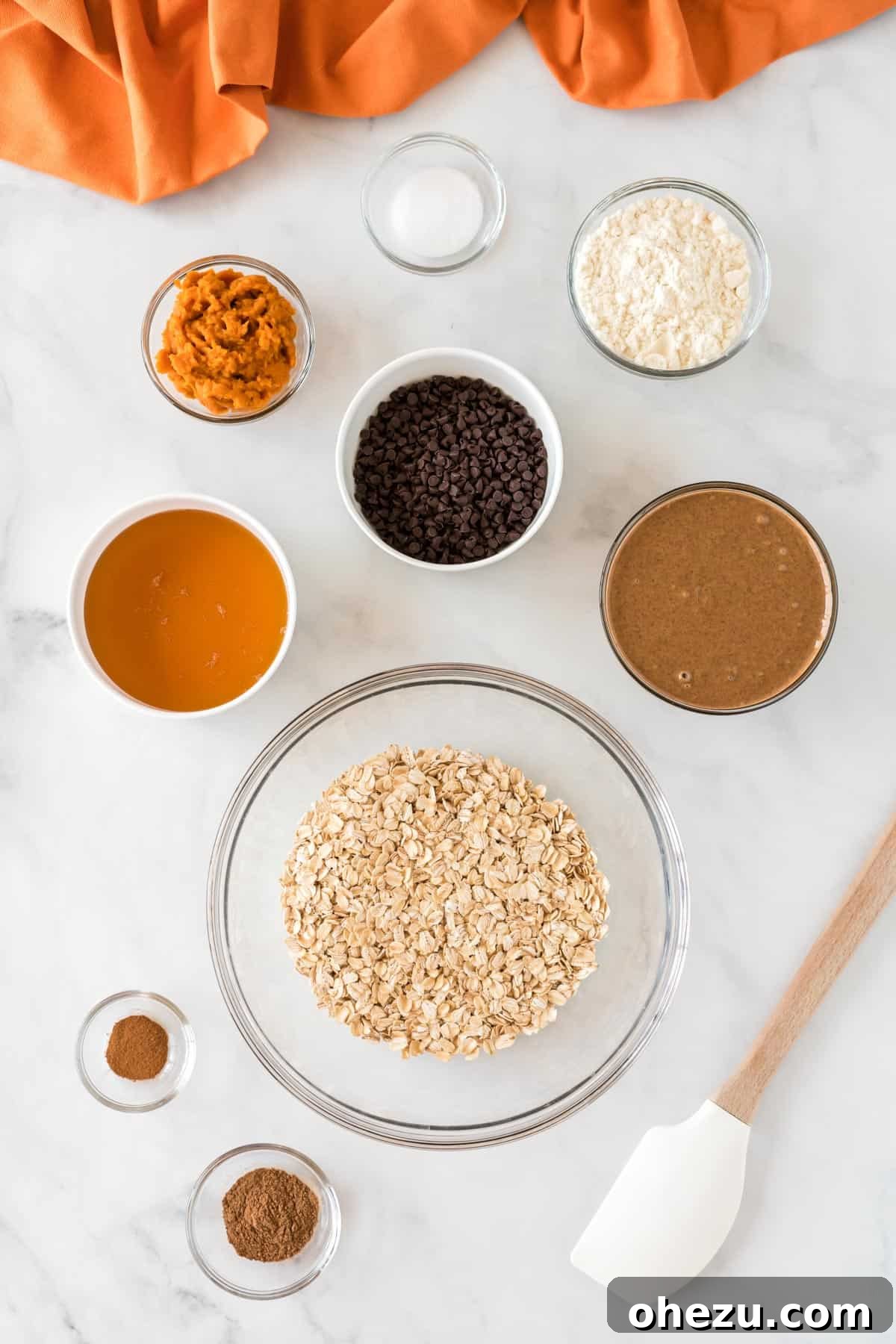 A collection of fresh ingredients laid out on a clean surface, including canned pumpkin, almond butter, rolled oats, and spices, ready to be combined for pumpkin energy balls.
