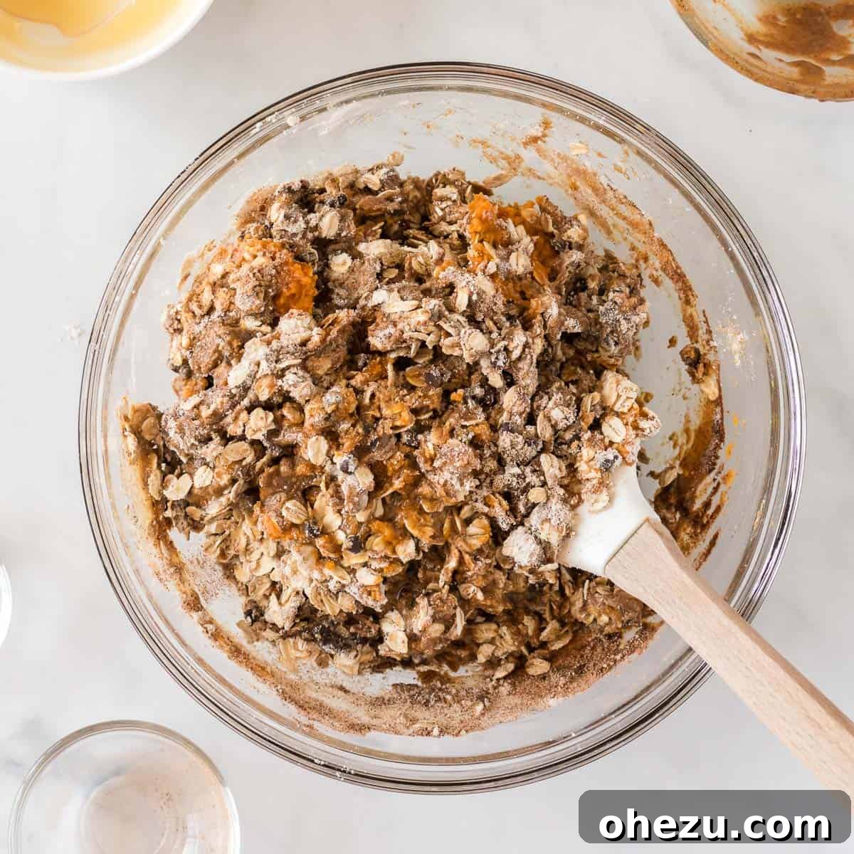 A close-up view of the energy ball dough being mixed with a spatula in a bowl, showing its thick and textured consistency.