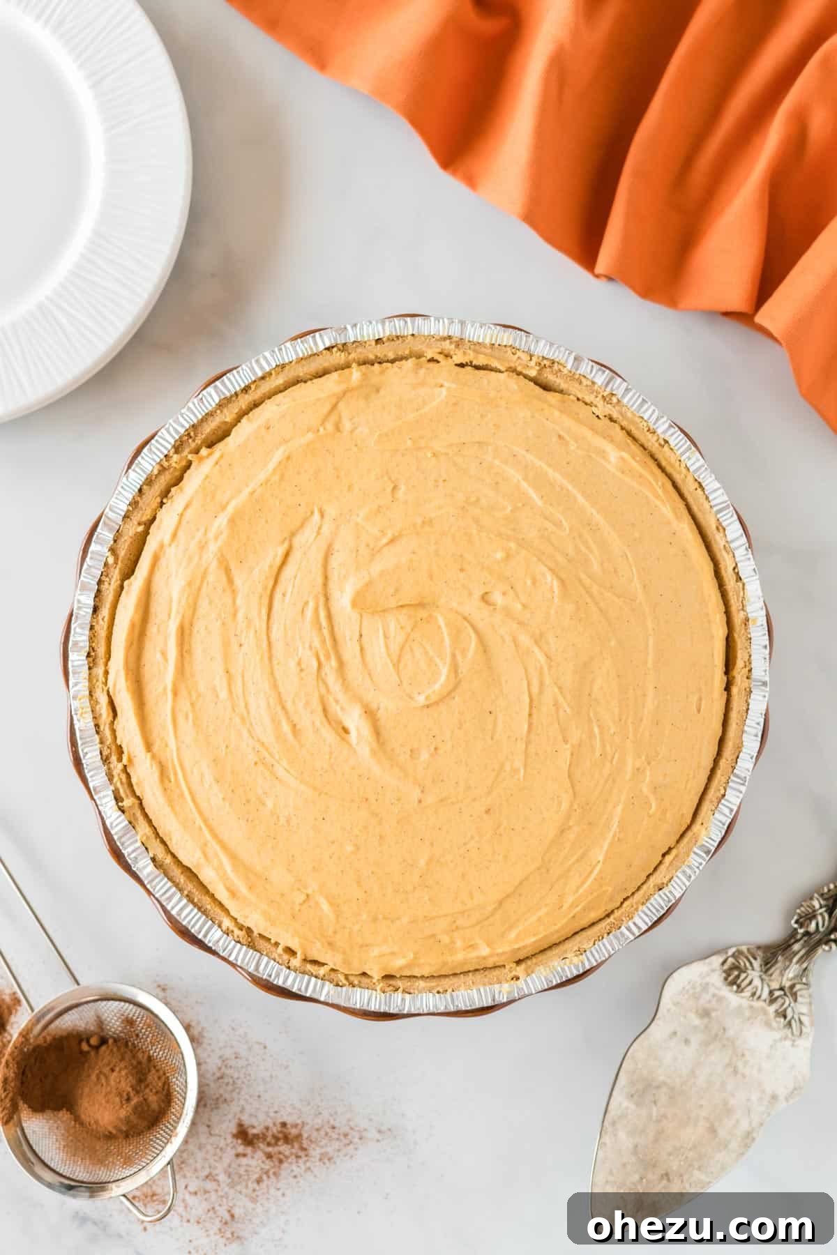 Velvet Pumpkin Pie 12 A freshly made no-bake pumpkin pie, covered with plastic wrap, being placed into the refrigerator to chill and set.