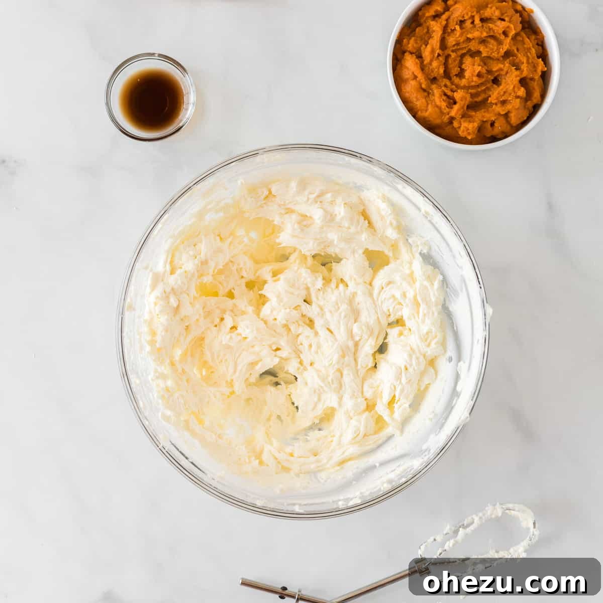 Velvet Pumpkin Pie 6 Softened cream cheese being beaten until fluffy and smooth in a bowl.