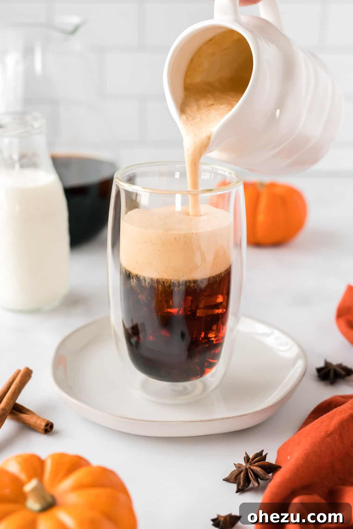 Spiced Pumpkin Cold Brew 2 Pouring rich, creamy pumpkin cold foam over a tall glass of dark cold brew coffee, creating a beautiful swirl of autumn flavors.