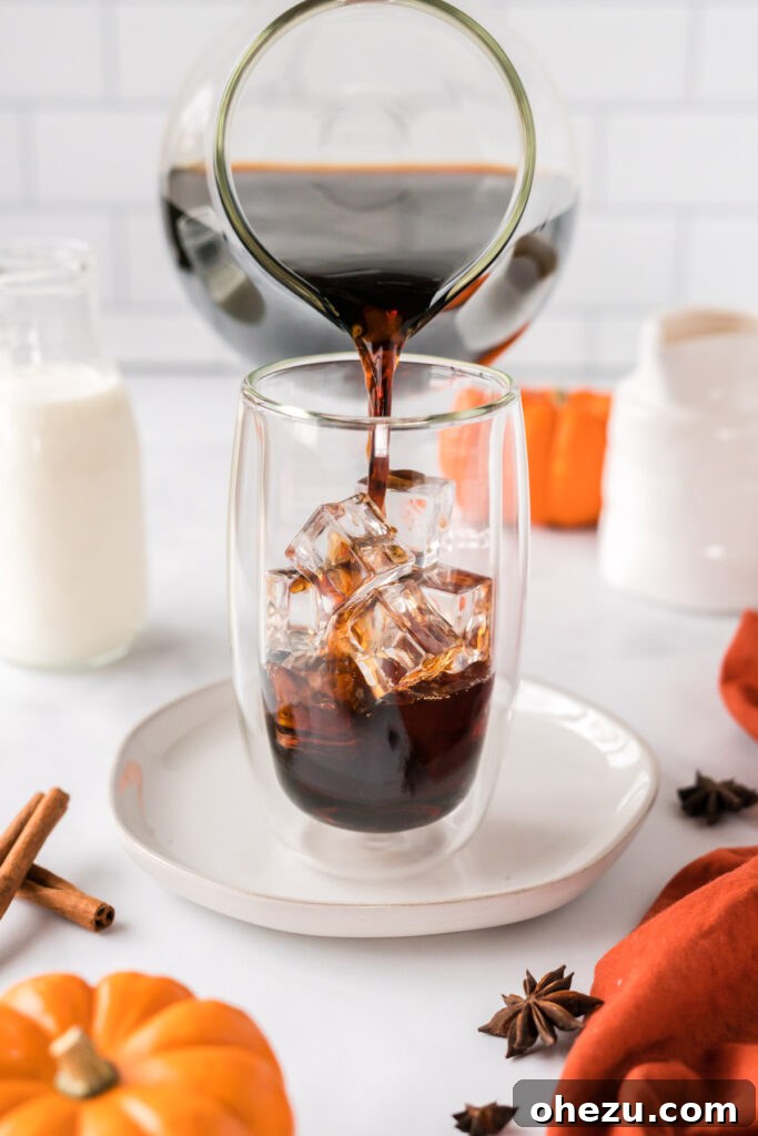 Spiced Pumpkin Cold Brew 8 A steady stream of dark cold brew coffee being poured over ice in a tall glass, creating a refreshing base.