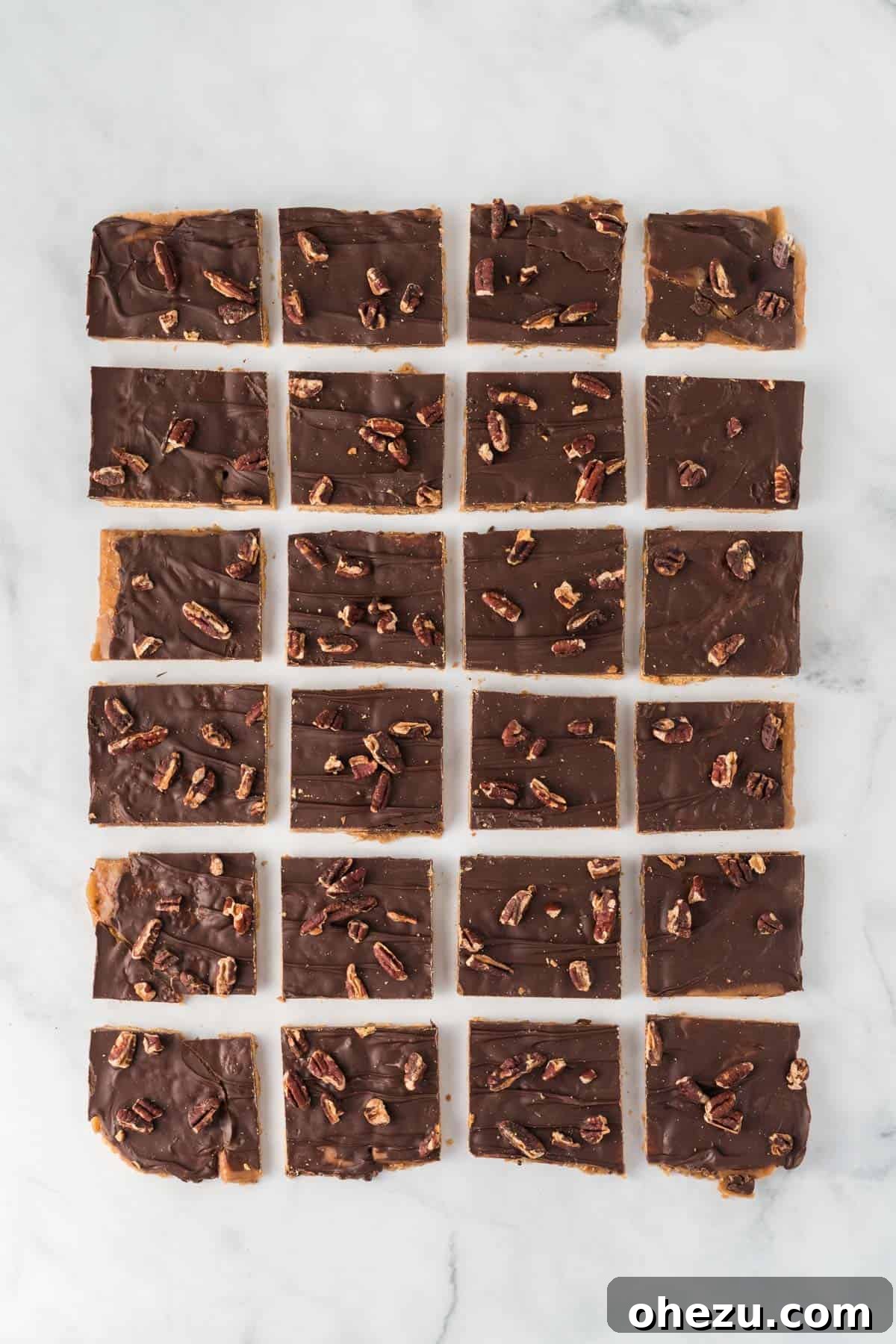 Neatly cut squares of graham cracker toffee arranged on a platter, clearly showing the distinct layers of cracker, golden toffee, rich chocolate, and toasted pecans.