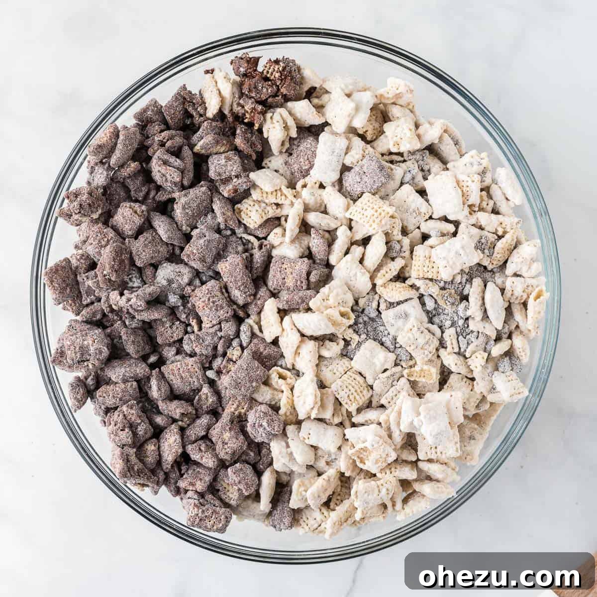 Cookies and Cream Puppy Chow 13 Both chocolate and white chocolate muddy buddies combined in a large serving bowl, ready to be mixed and served.