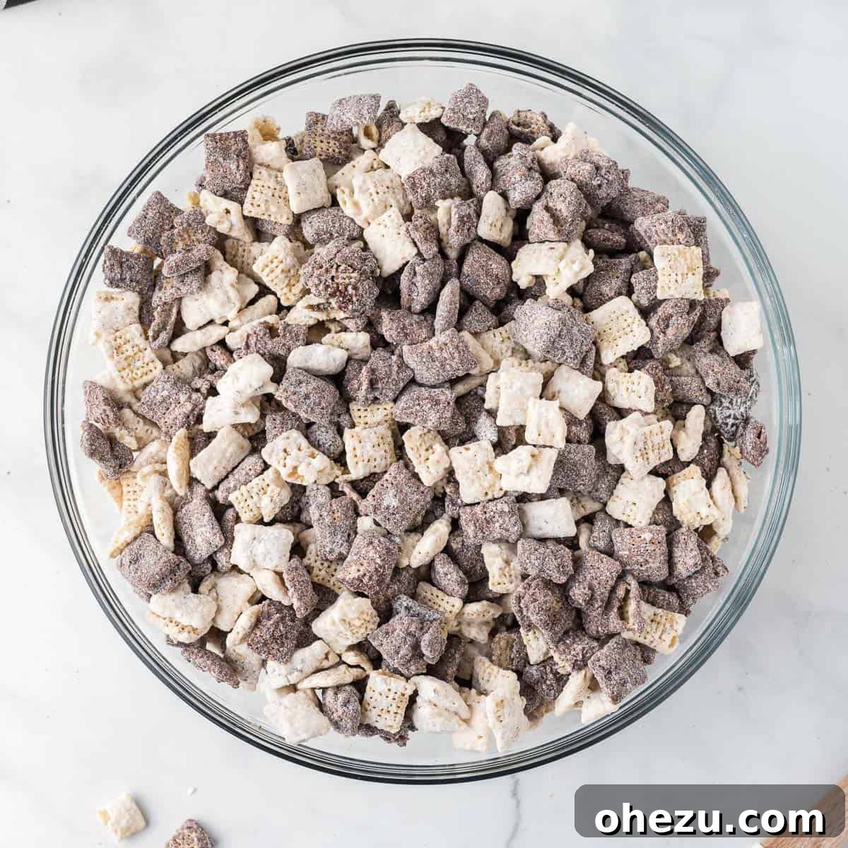 Cookies and Cream Puppy Chow 14 A close-up shot of the mixed chocolate and white chocolate muddy buddies in a large bowl, highlighting their texture and coating.