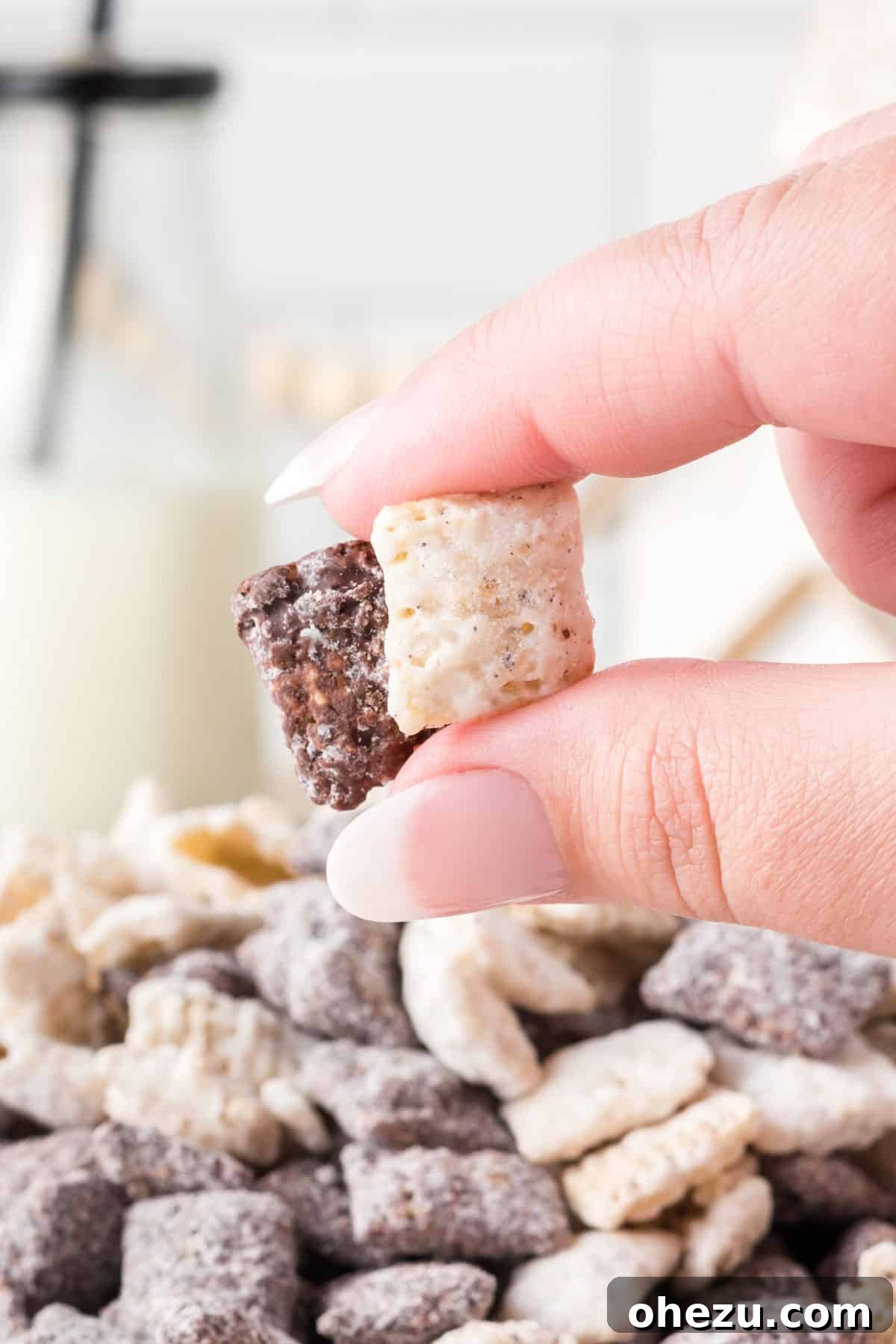 Cookies and Cream Puppy Chow 15 A hand holding a small handful of Cookies and Cream Muddy Buddies, showing the delicious coating.