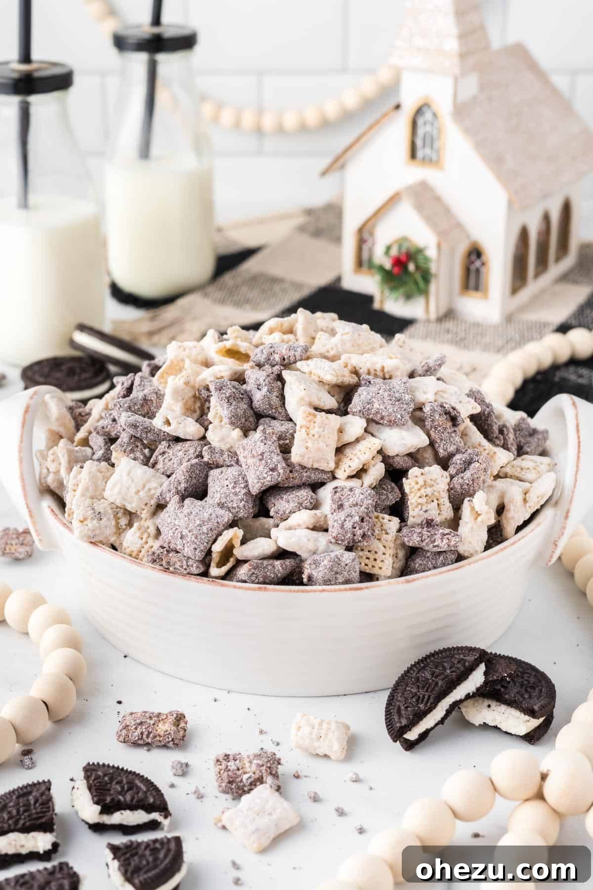 Cookies and Cream Puppy Chow 16 A large serving bowl full of Cookies and Cream Muddy Buddies, with festive Christmas decorations blurred in the background, ready for a holiday party.
