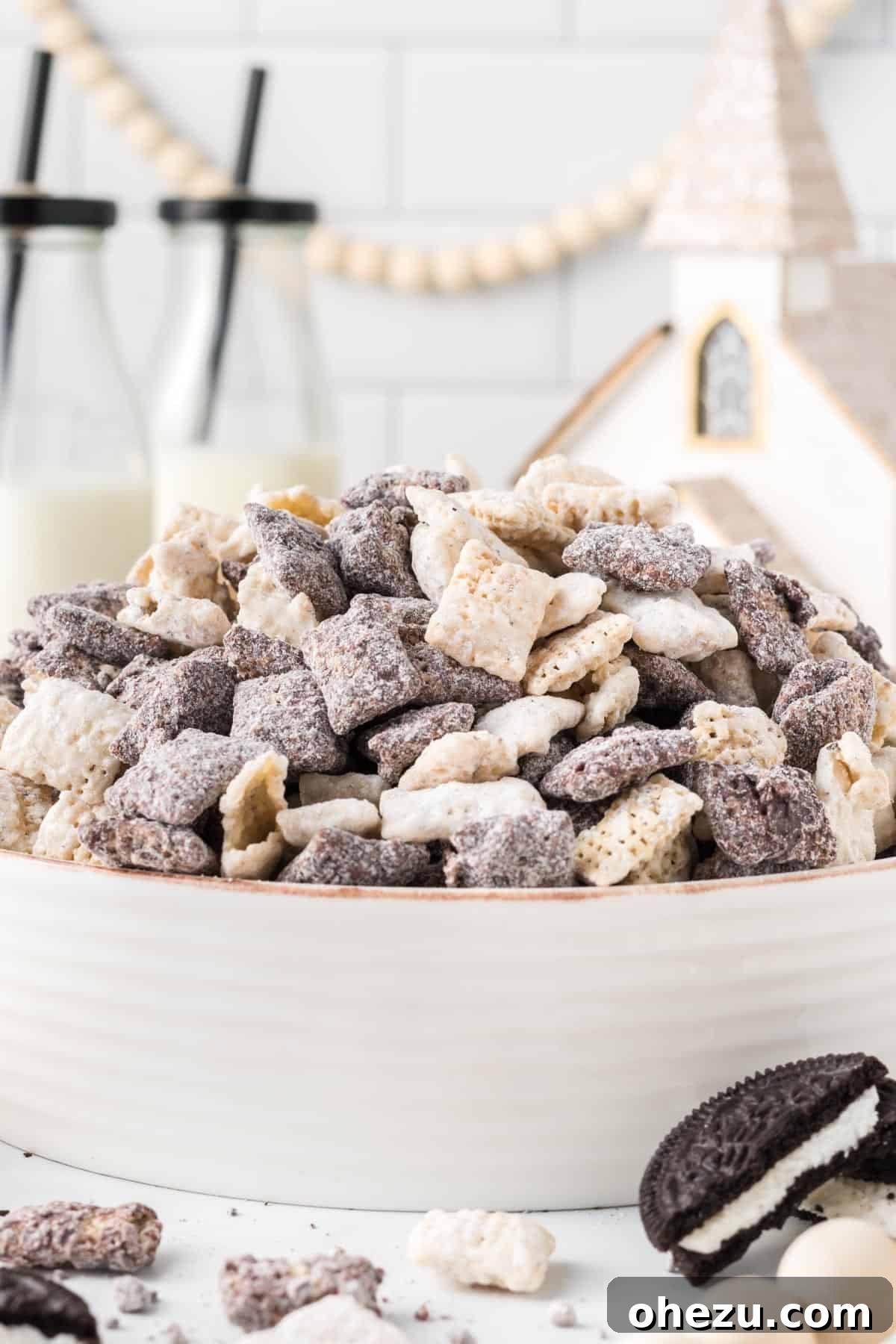 Cookies and Cream Puppy Chow 3 A large serving bowl overflowing with Cookies and Cream Muddy Buddies, presented in a festive Christmas setting.