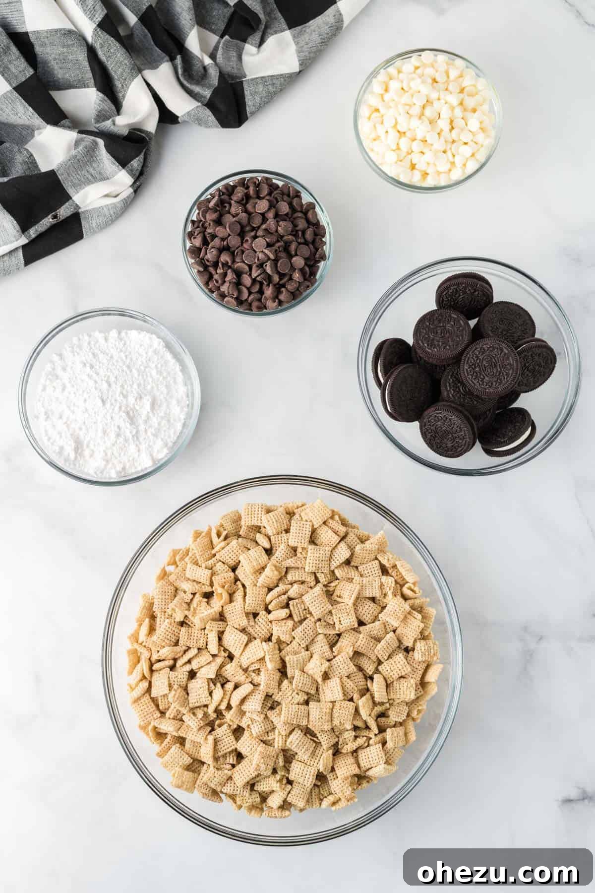Cookies and Cream Puppy Chow 4 All five ingredients laid out: Rice Chex cereal, semi-sweet chocolate chips, white chocolate chips, Oreos, and powdered sugar, ready to make cookies and cream muddy buddies.