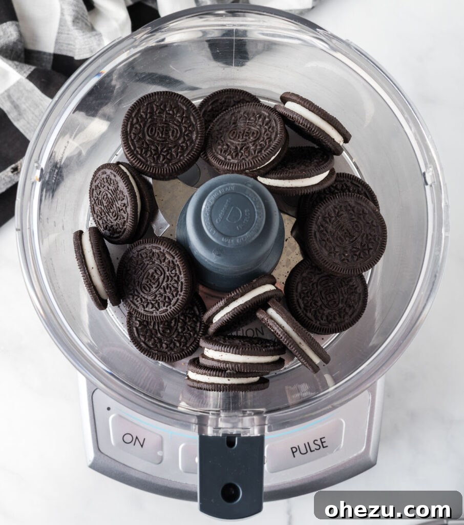 Cookies and Cream Puppy Chow 5 Oreos being added to a food processor to be crushed.