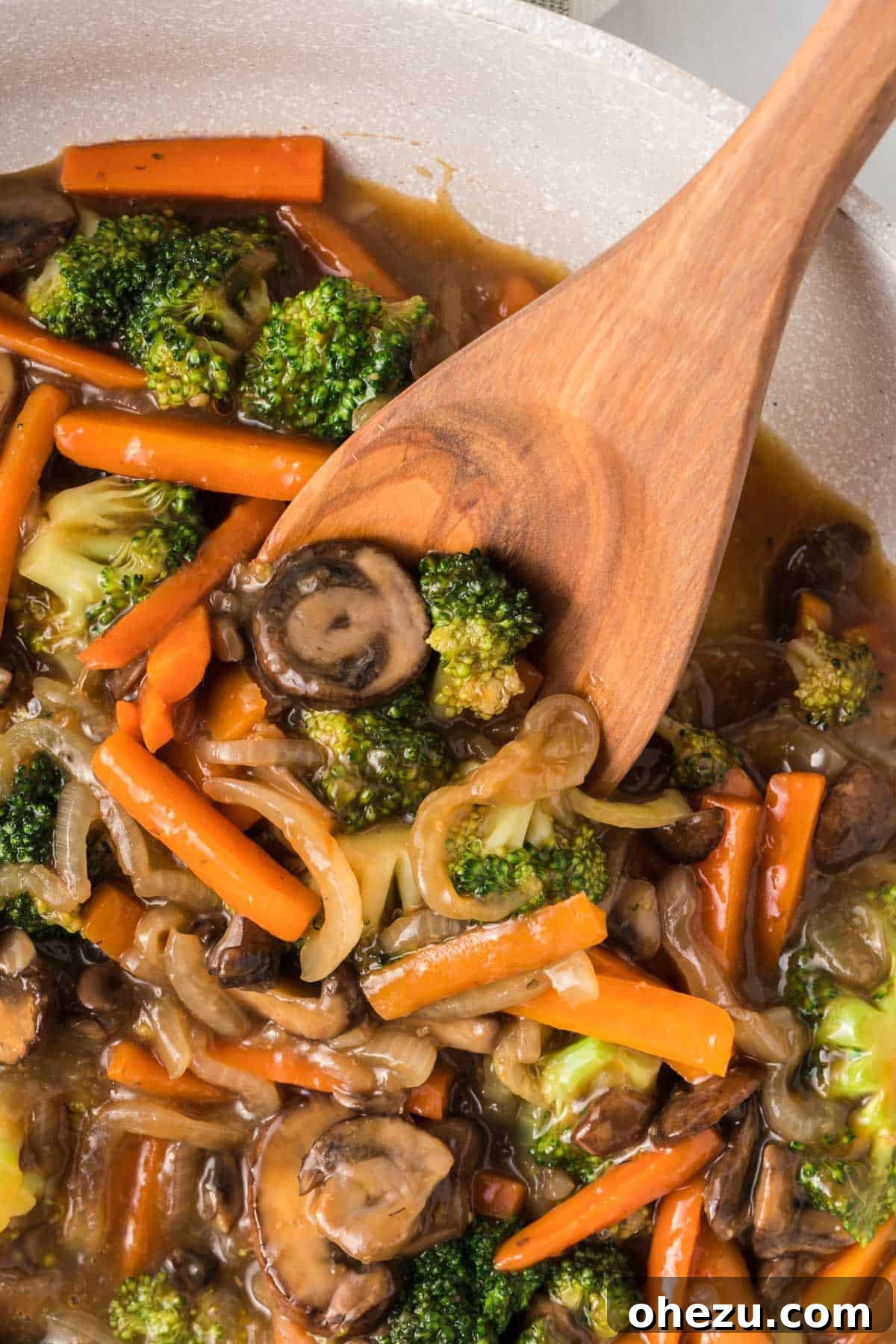 A wooden spoon serving a generous helping of vibrant, saucy teriyaki vegetables into a bowl, emphasizing portion size.