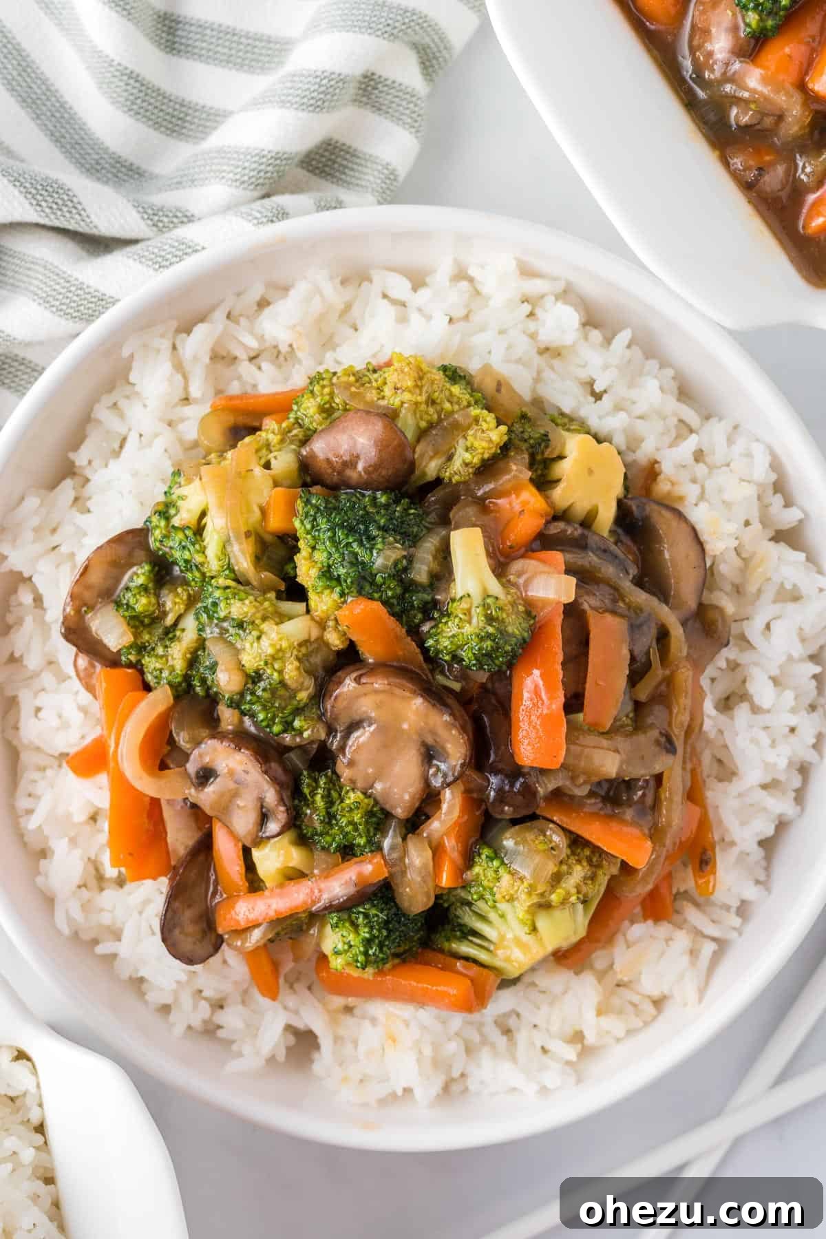 A beautifully presented bowl of teriyaki vegetables over white rice, garnished with sesame seeds, showcasing a complete and appetizing meal.