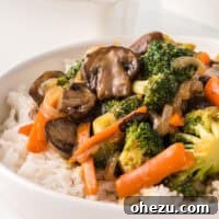 A close-up of a bowl filled with colorful teriyaki vegetables over white rice, showcasing the finished dish.
