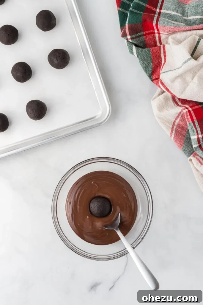 Decadent Holiday Oreo Treats 12 An Oreo ball being carefully dipped into a bowl of melted dark chocolate