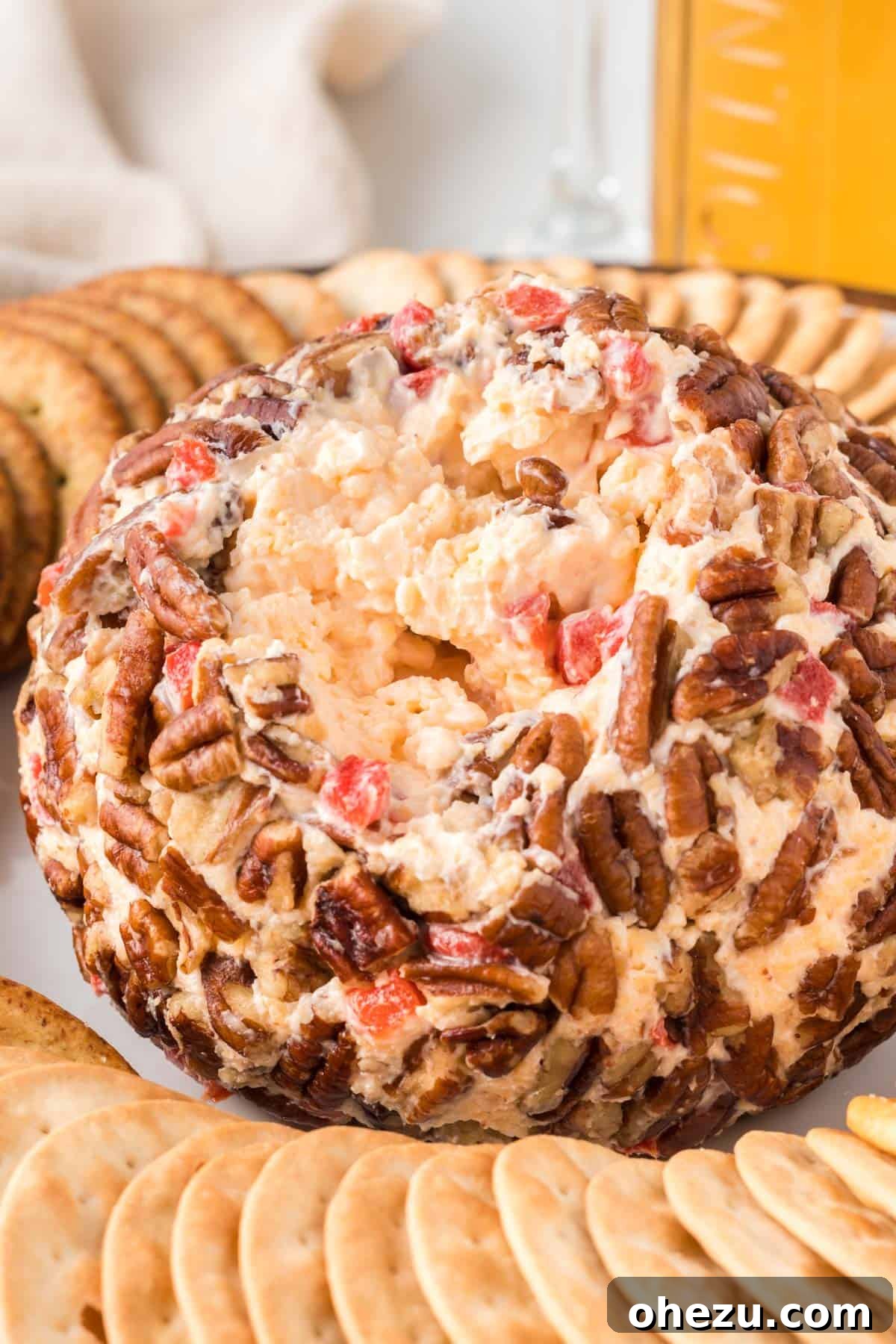 pimento cheese ball on a platter with a portion already served, showing the creamy interior