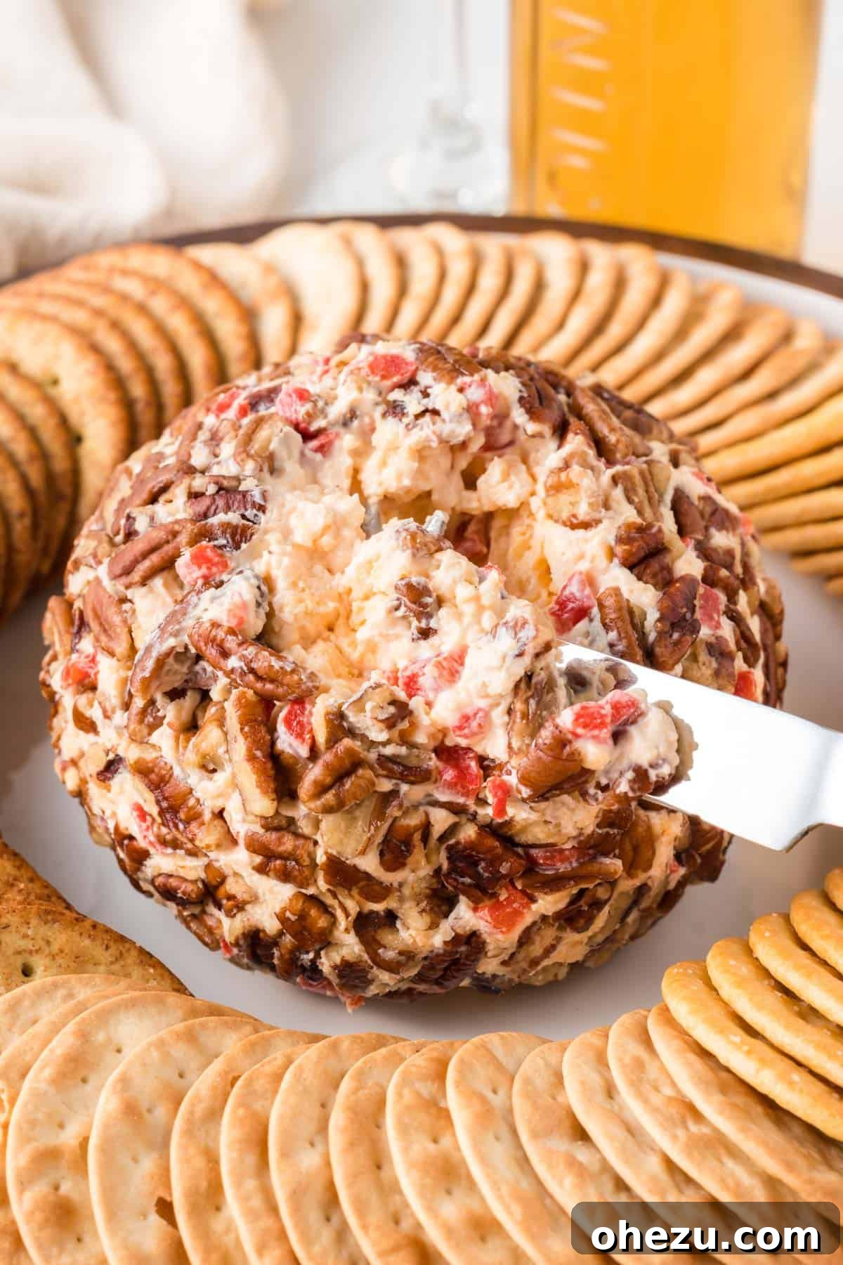 serving knife gently placed in the center of the pimento cheese ball, showcasing its texture