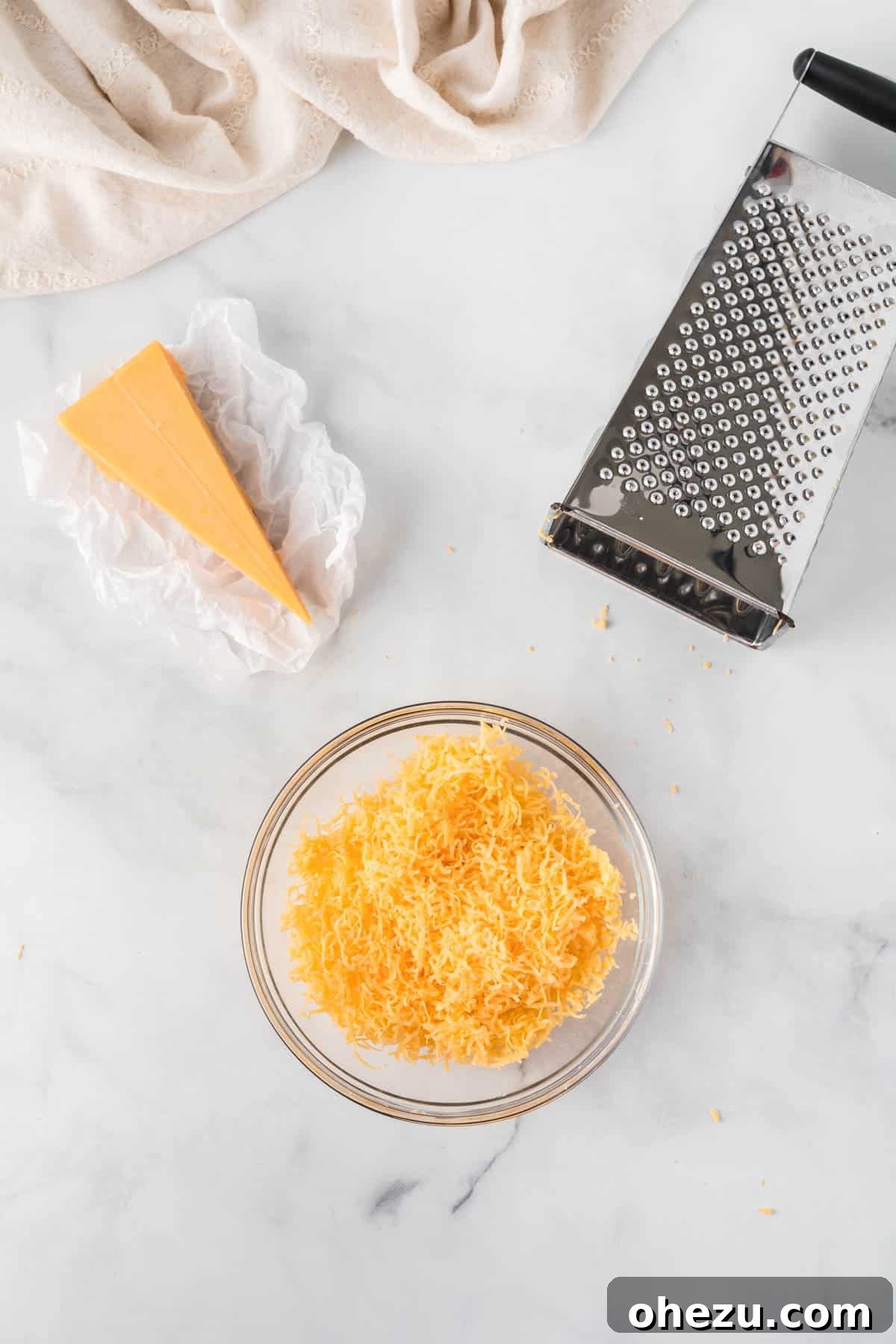 freshly grated cheddar cheese in a mixing bowl, ready for the next step