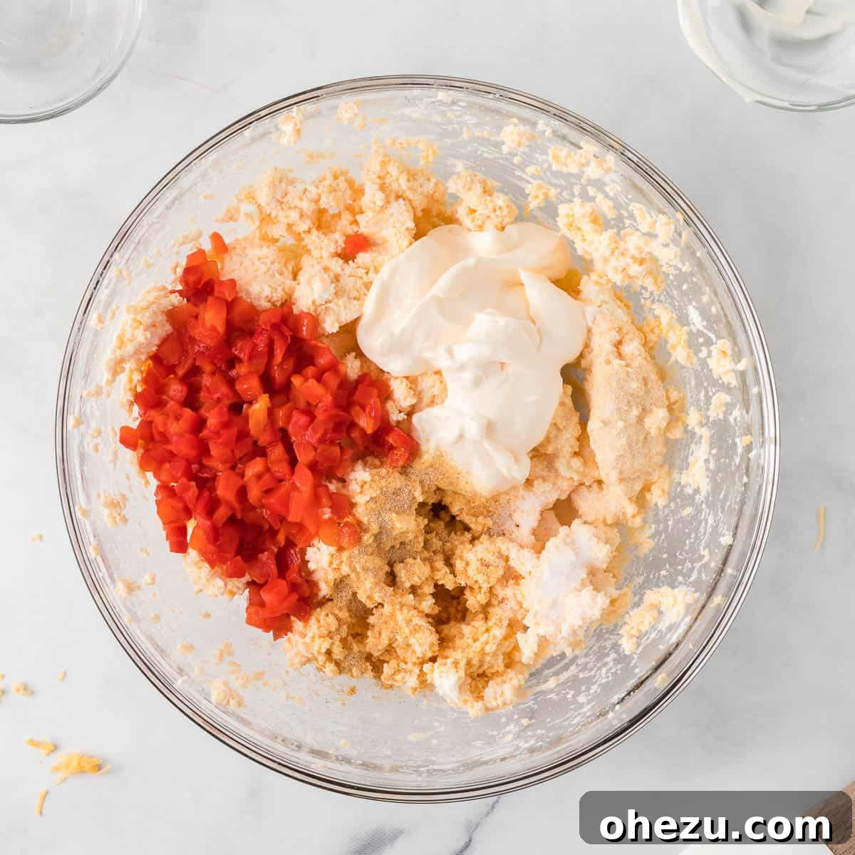 drained pimentos, mayonnaise, and spices added to the creamy cheese mixture in a bowl