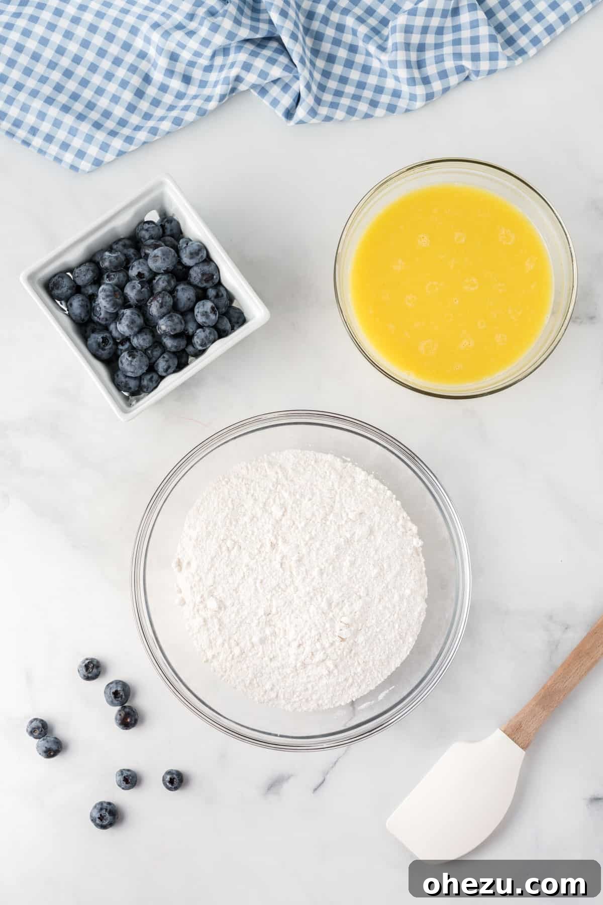 A visual representation showing the cake mix in a bowl, wet ingredients in another, and a pile of fresh blueberries, all poised for mixing