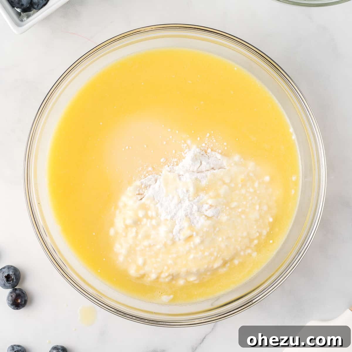 The process of adding the liquid wet ingredients to the dry cake mix in a bowl, preparing to stir