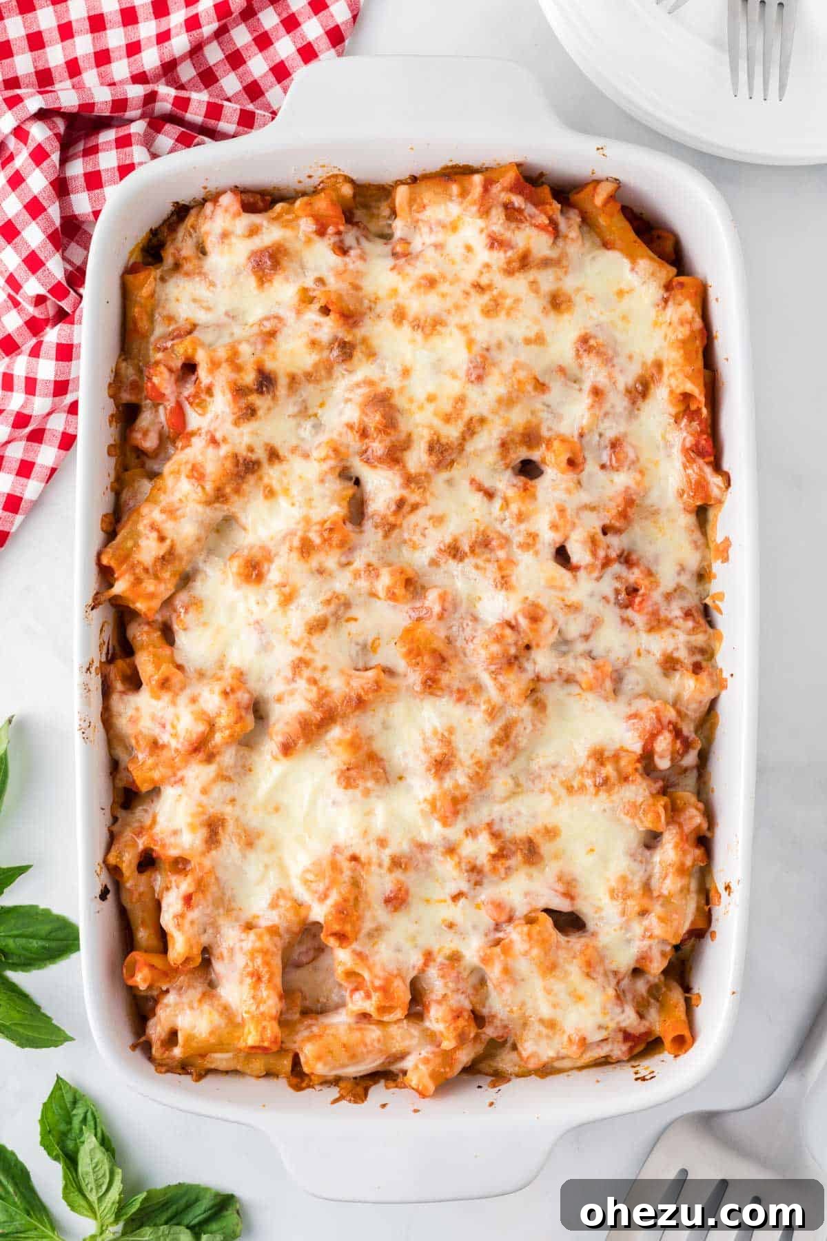 Close-up of a bubbling Vegetarian Baked Ziti in a casserole dish, topped with golden-brown cheese.