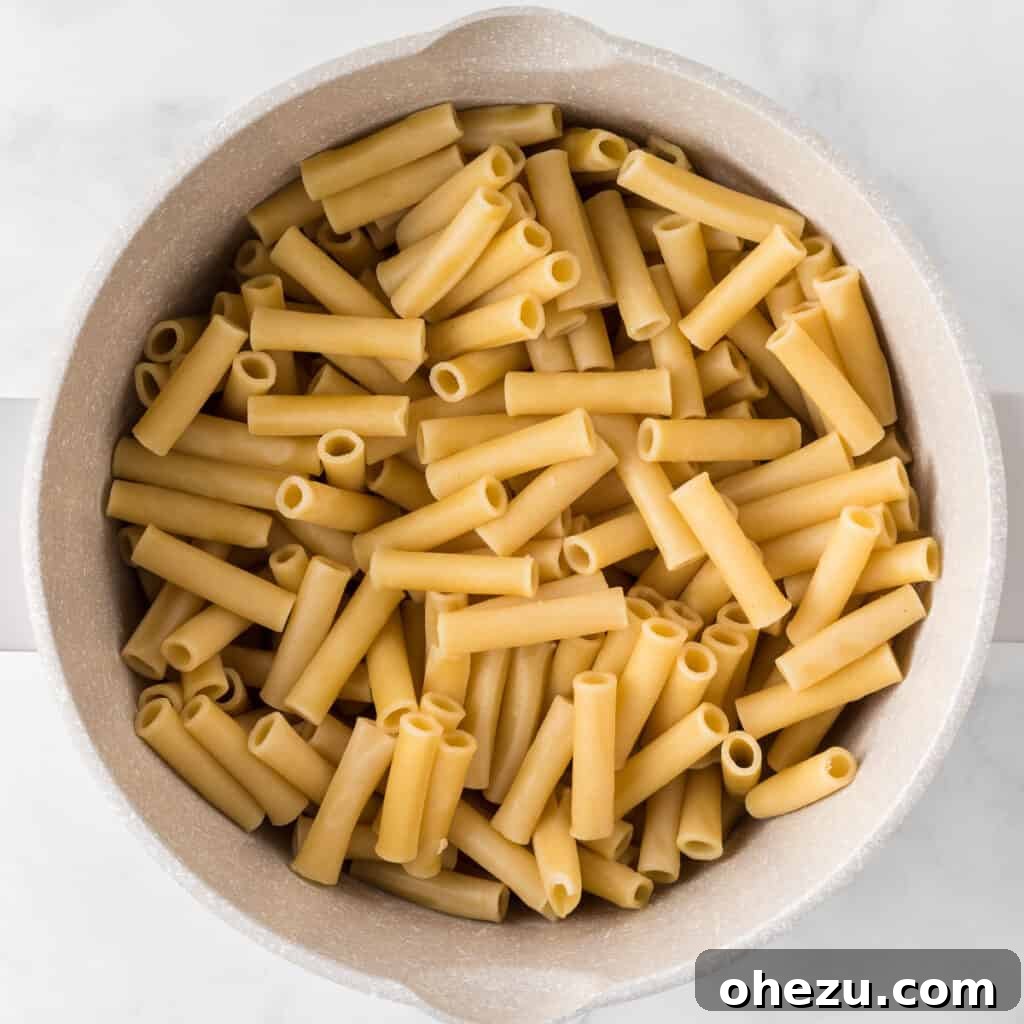 Cooked ziti pasta noodles in a saucepan, ready to be mixed with the sauce and vegetables.