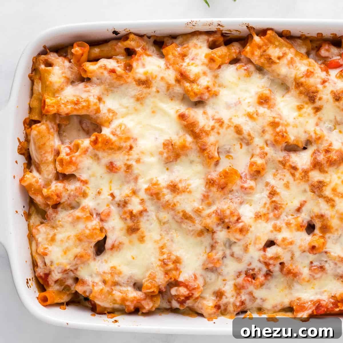 A full casserole dish of vegetarian baked ziti, hot and ready to serve, showing off its irresistible golden cheese topping and rich sauce.