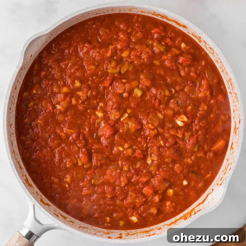 The pasta sauce beautifully mixed with the colorful sautéed vegetables in the skillet, simmering gently.