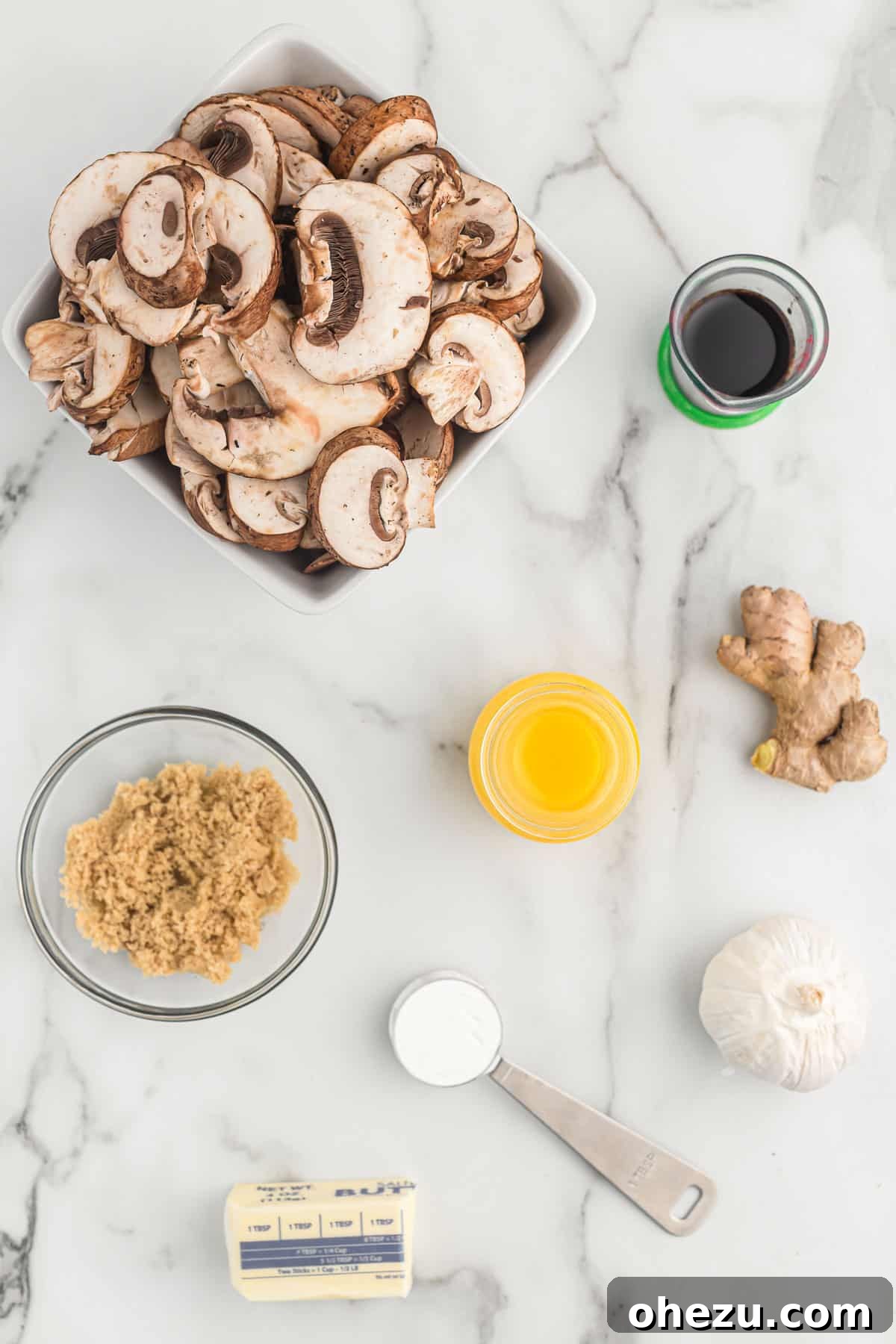 A vibrant collection of fresh ingredients carefully laid out, including perfectly sliced mushrooms, aromatic garlic cloves, rich butter, and all the essential components for crafting a homemade teriyaki sauce.