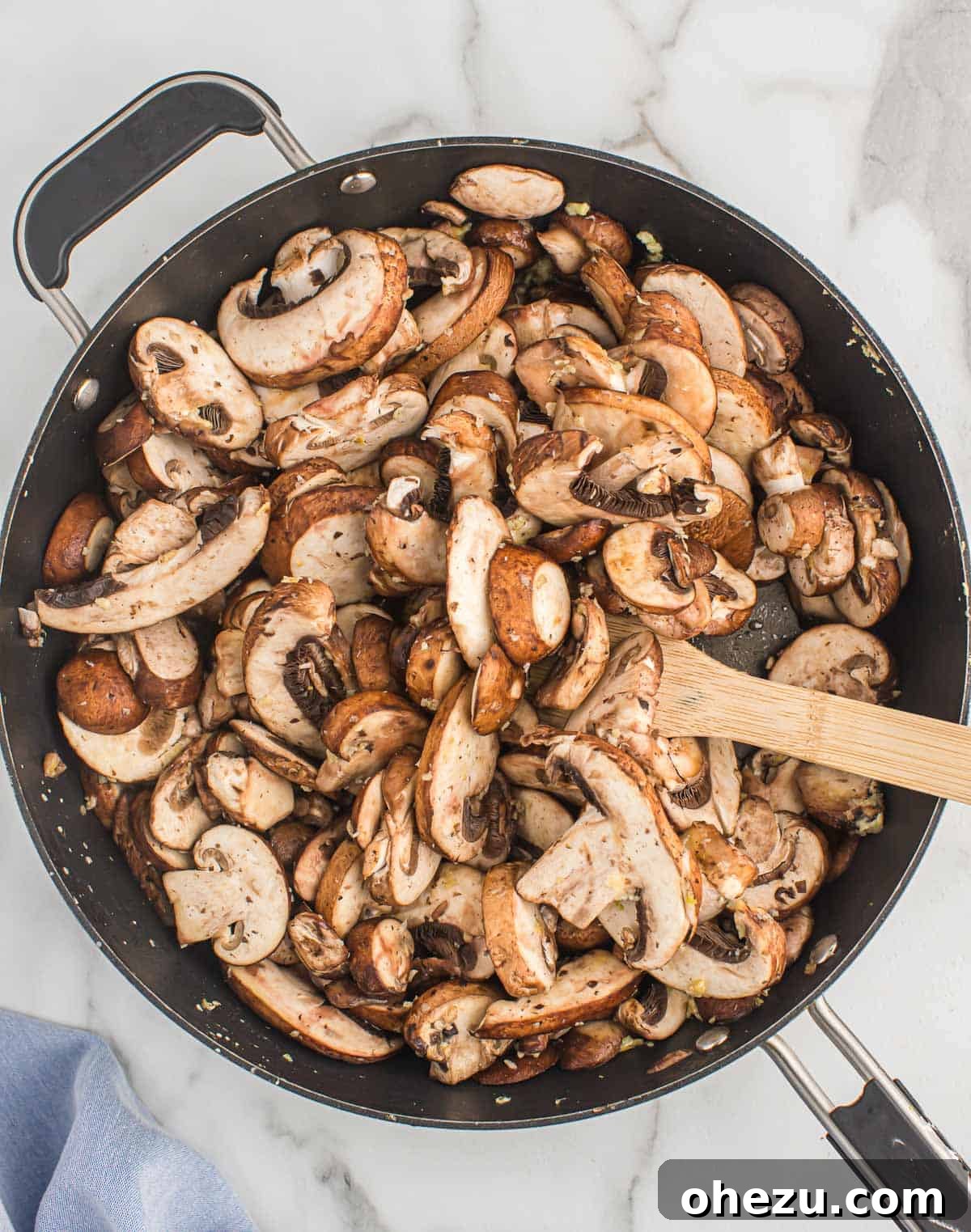 Freshly sliced mushrooms being carefully added to a hot skillet containing melted butter, initiating the pan-frying process.