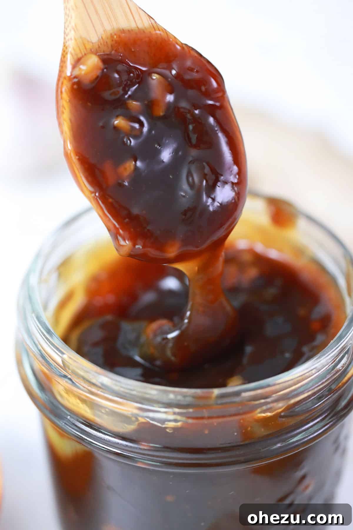 A wooden spoon delicately dripping rich, homemade teriyaki sauce, perfectly illustrating its thick and appealing consistency.