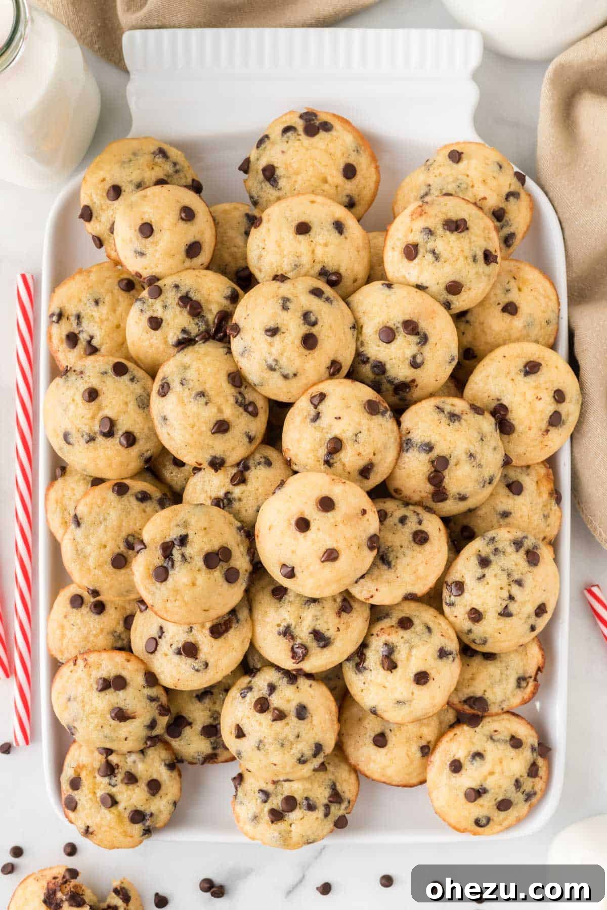 Stacked mini chocolate chip muffins on a white platter, invitingly displayed.