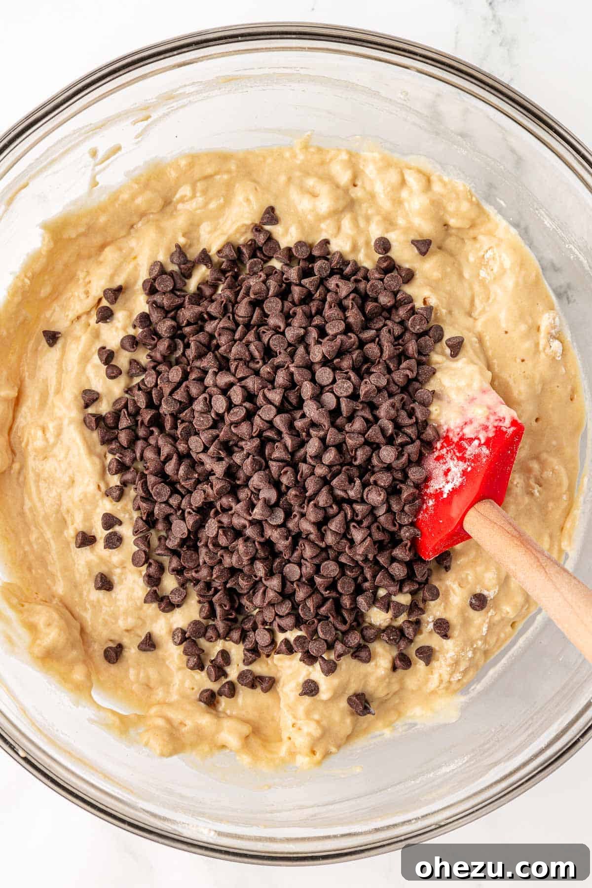 Mini chocolate chips being added to the prepared muffin batter.