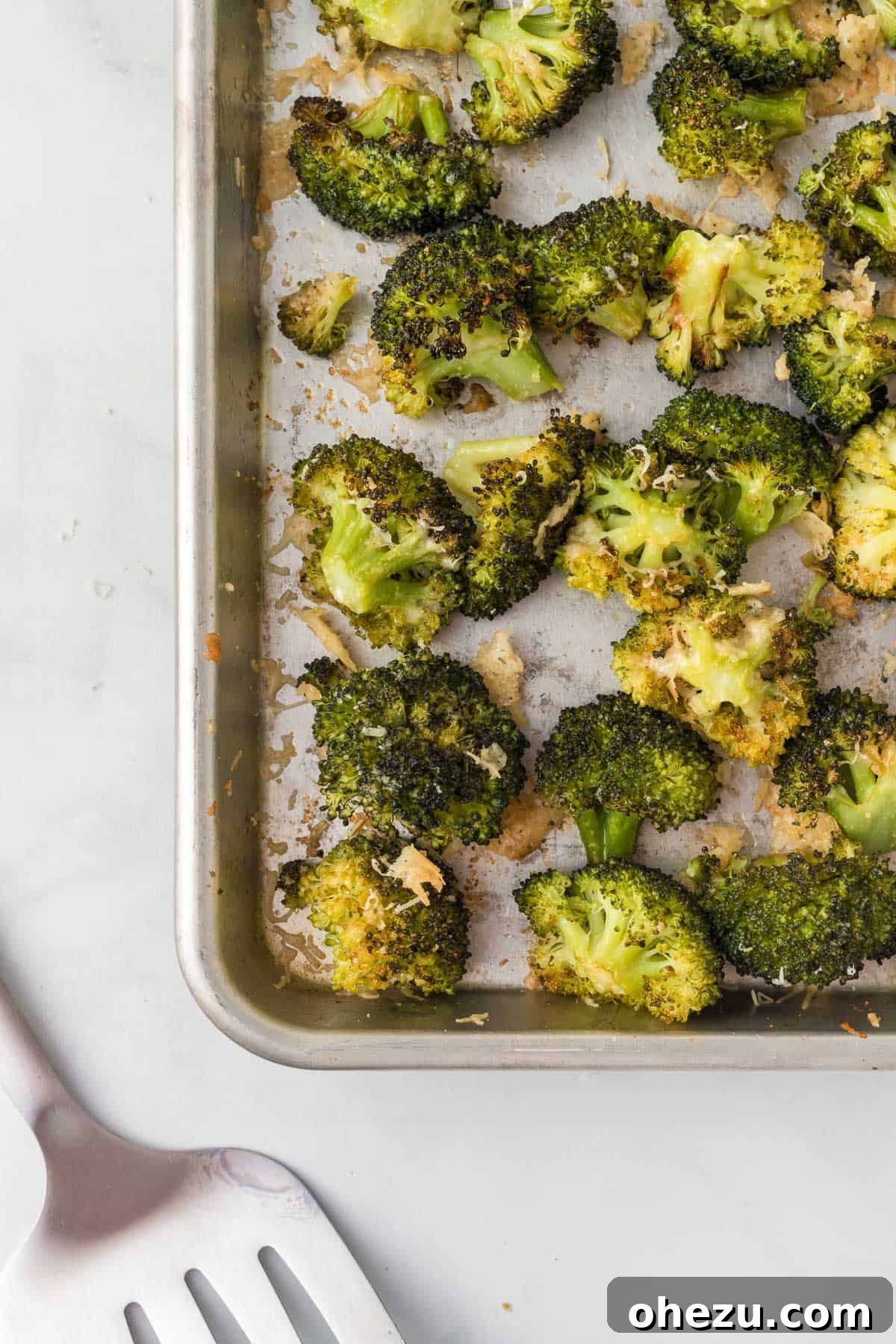Crispy Parmesan Roasted Broccoli 2 Crispy roasted broccoli with golden parmesan cheese on a baking sheet, fresh out of the oven
