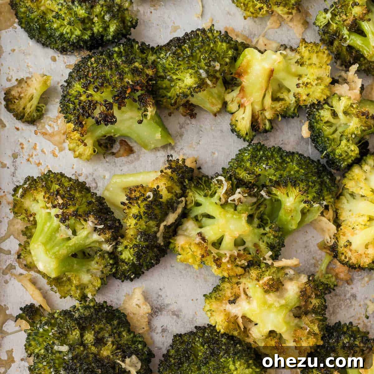 Crispy Parmesan Roasted Broccoli 13 Close-up photo of roasted broccoli with crispy parmesan cheese spread on a sheet pan, highlighting the texture and color