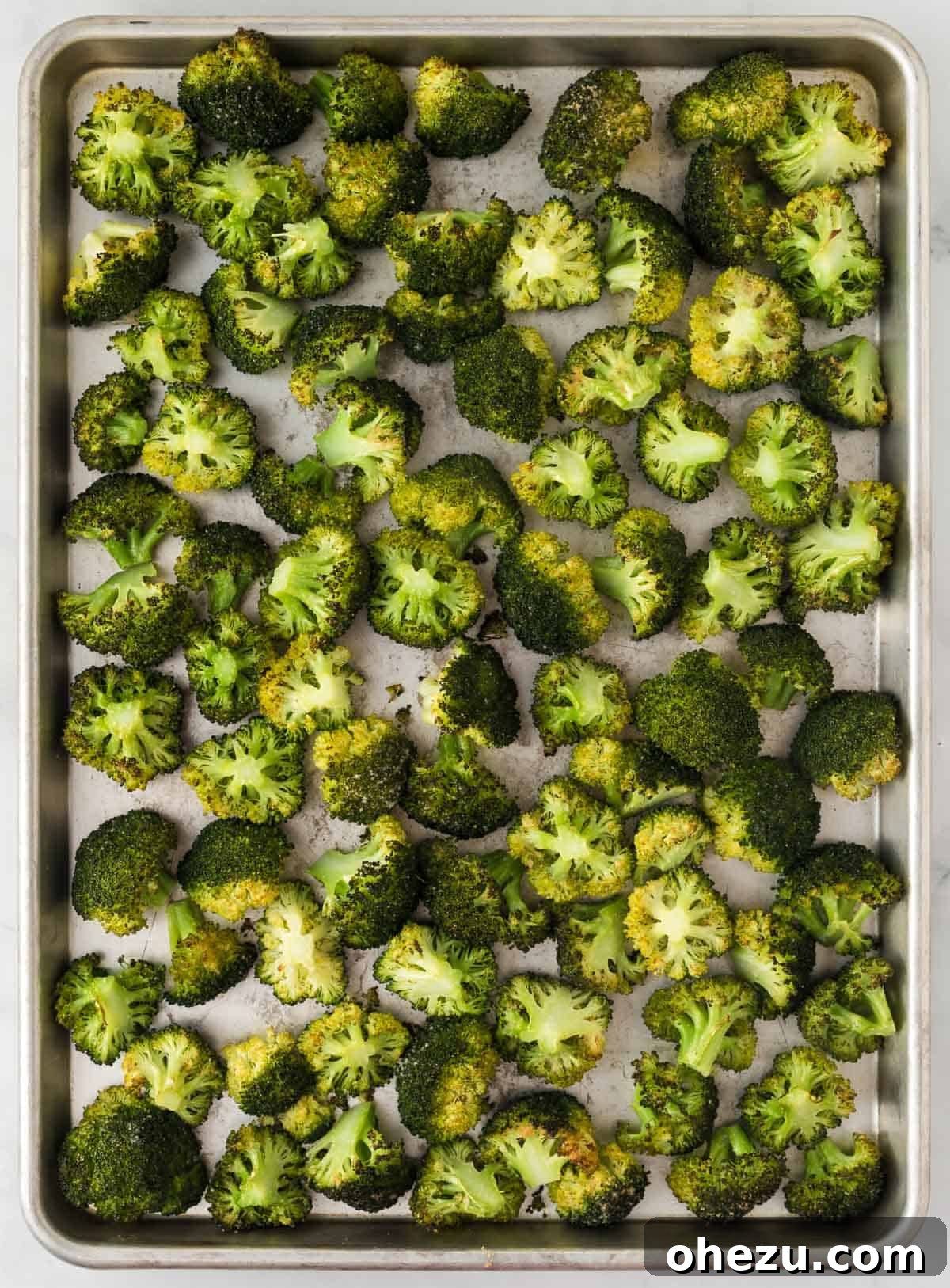 Crispy Parmesan Roasted Broccoli 9 Freshly roasted broccoli on a baking sheet, with visible crispy edges and melted, golden-brown parmesan cheese