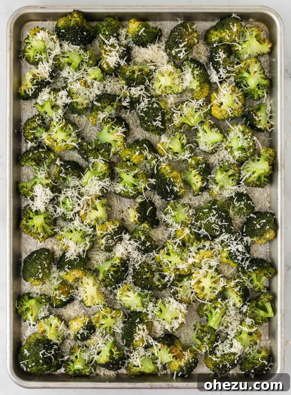 Crispy Parmesan Roasted Broccoli 10 A hand sprinkling freshly grated parmesan cheese over hot, roasted broccoli on a baking sheet