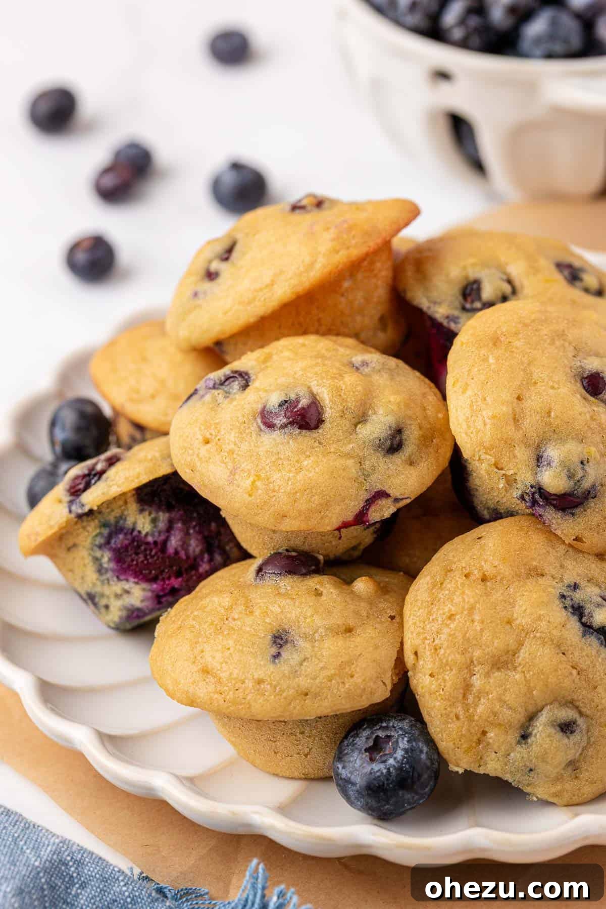 Blueberry Poppers 2 Delicious and fluffy blueberry mini muffins stacked on a plate, ready to be enjoyed.