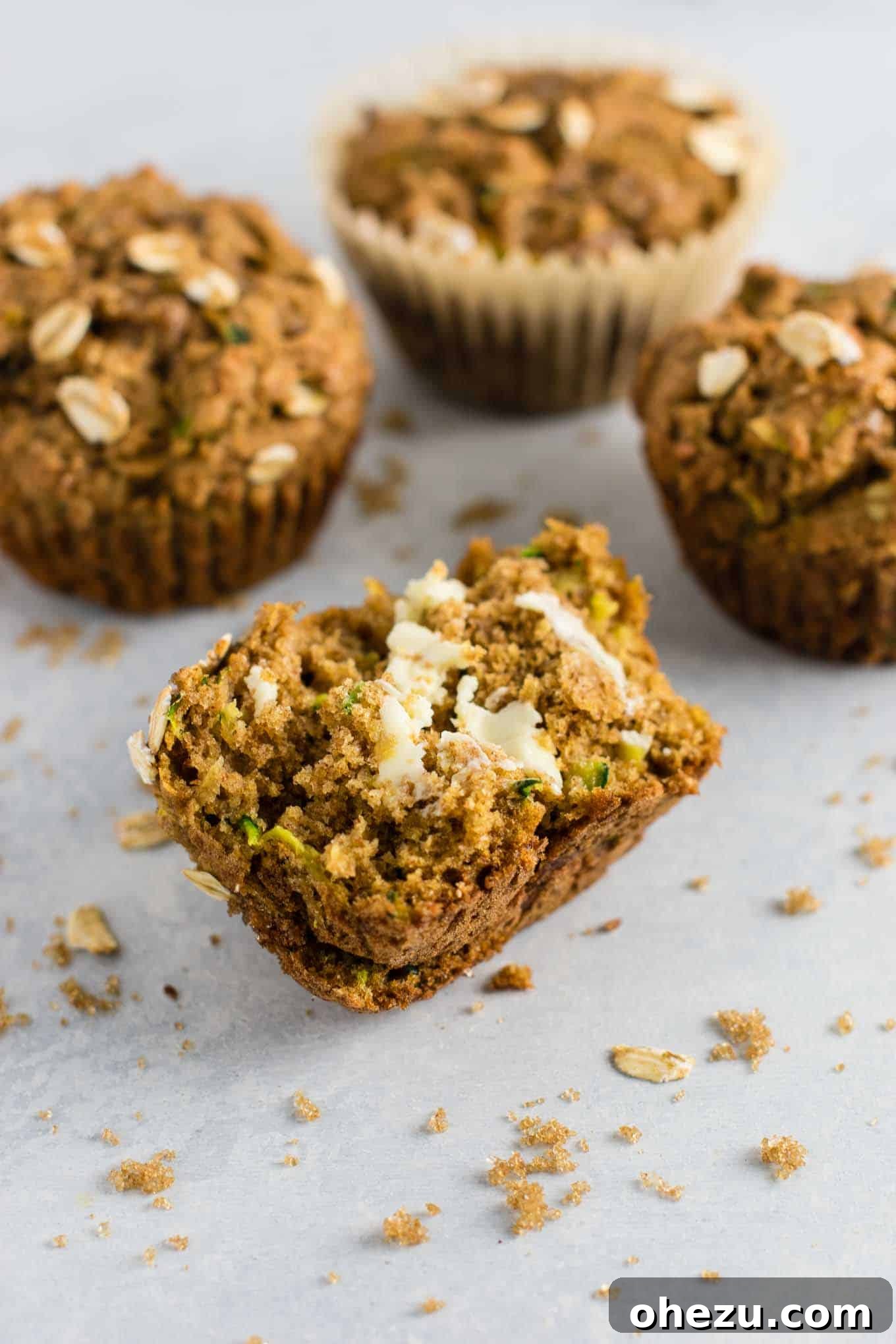 A hand holding a perfectly baked zucchini bread muffin, ready to be enjoyed.