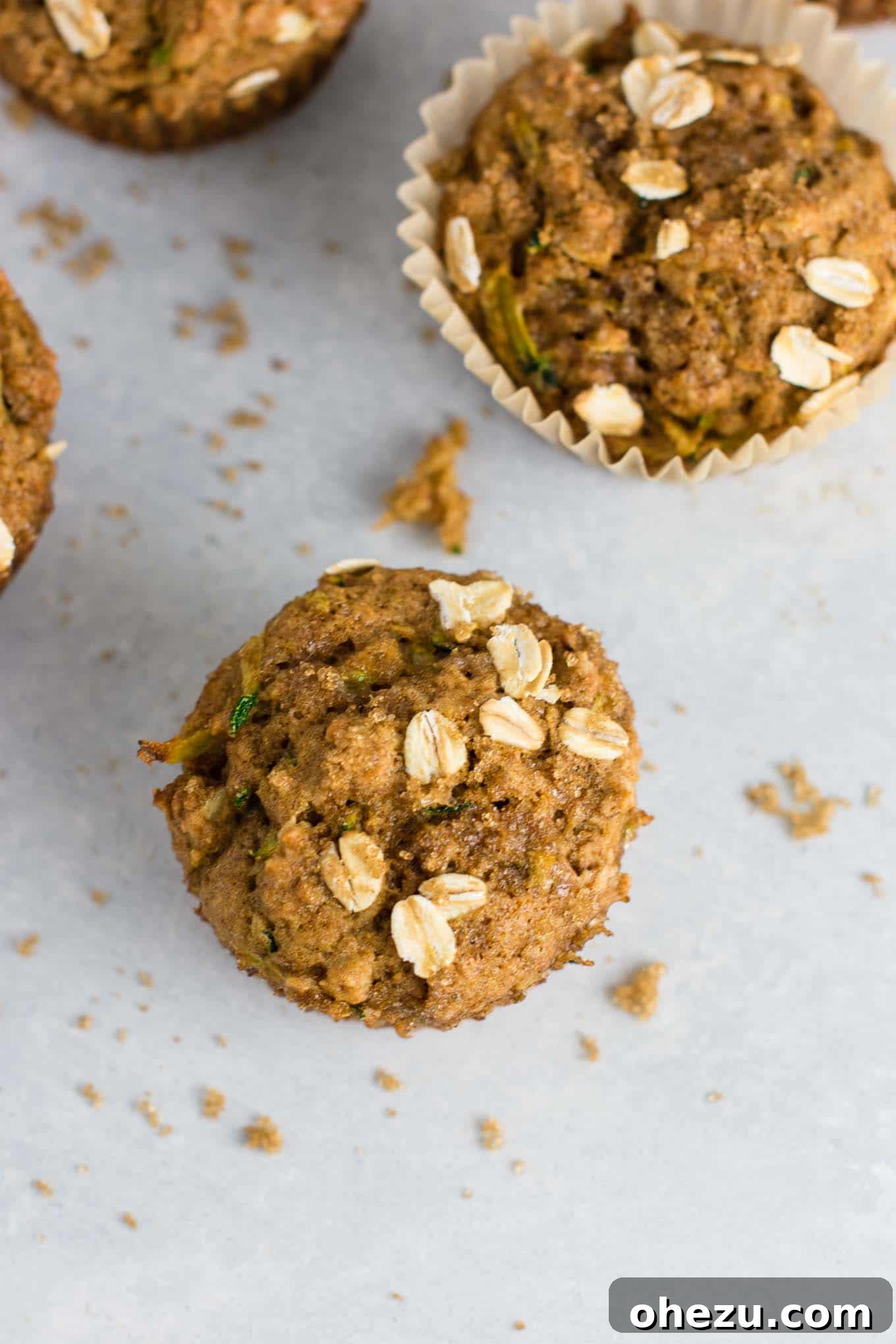 A stack of healthy zucchini muffins, topped with oats and a light dusting of brown sugar.
