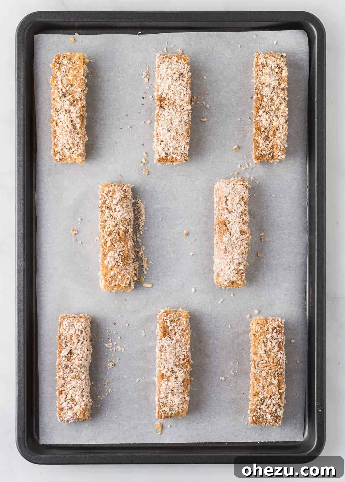 Vibrant Tofu Wraps 12 A baking sheet lined with parchment paper, holding several breaded tofu strips ready for baking.