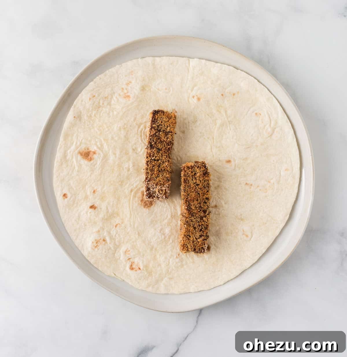 Vibrant Tofu Wraps 14 A warm flour tortilla with two crispy tofu strips placed centrally, ready for additional fillings.