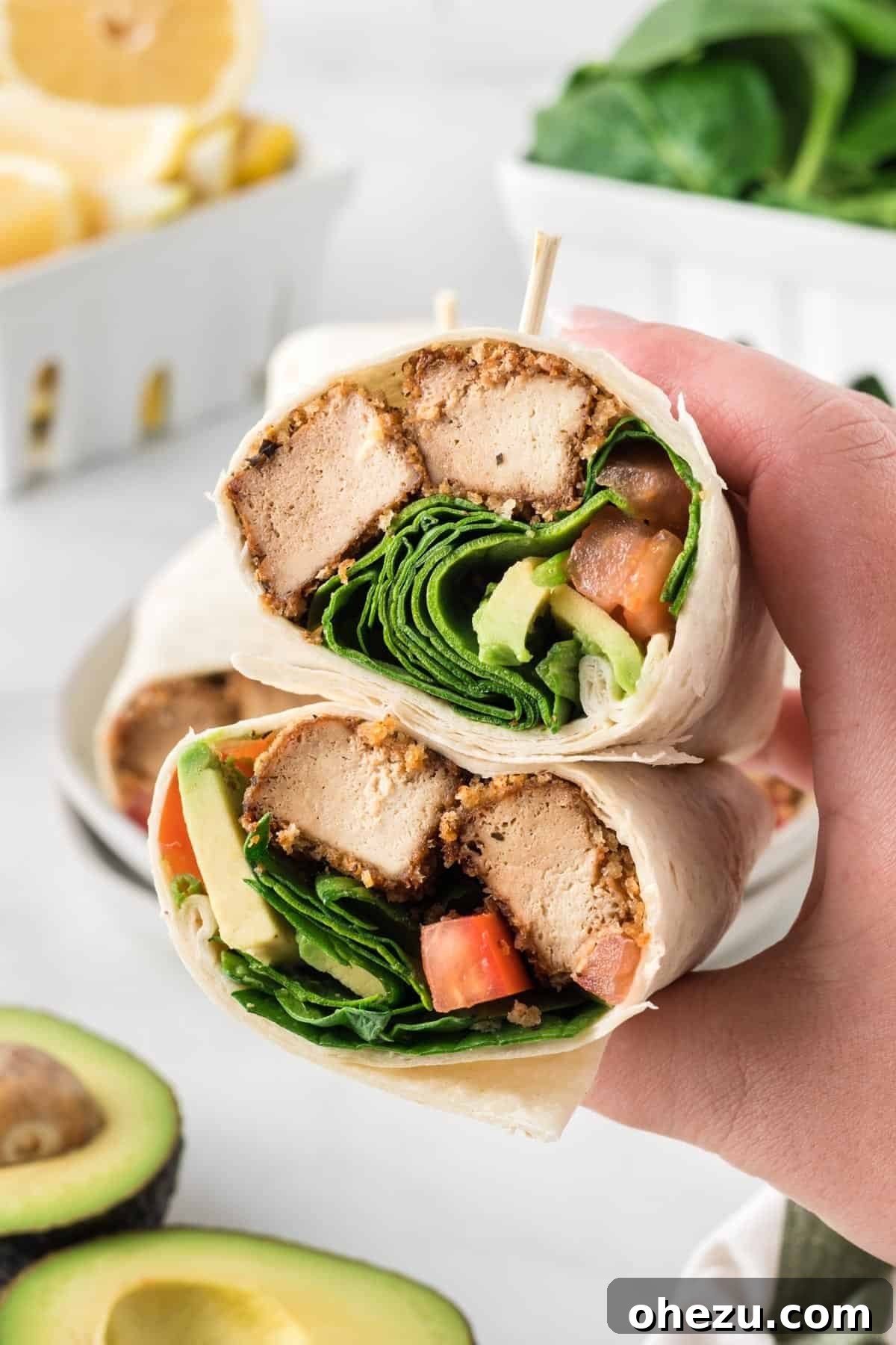 Vibrant Tofu Wraps 17 A hand holding a freshly cut tofu wrap, revealing the vibrant layers of crispy tofu, avocado, tomato, and spinach.