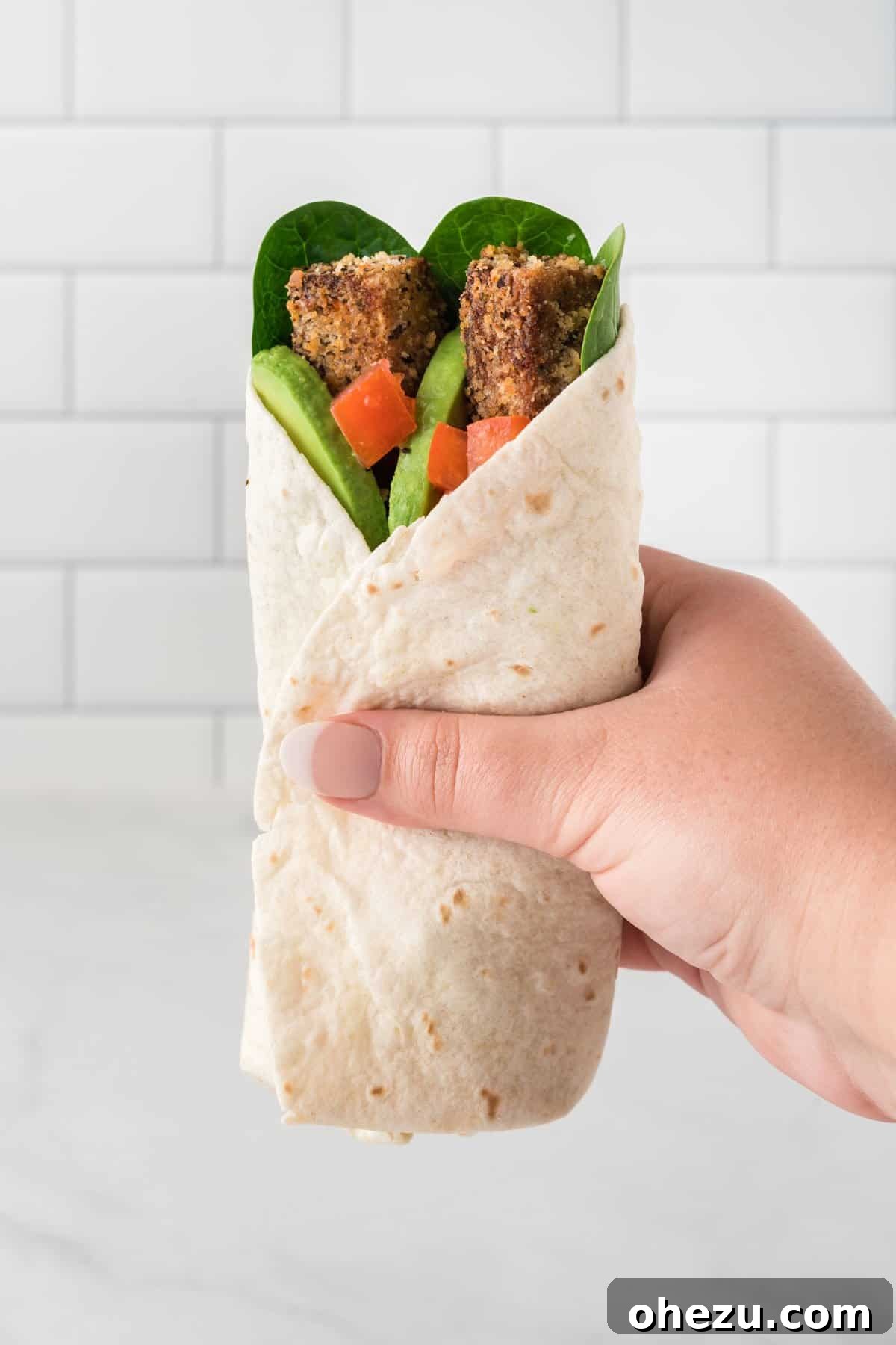 Vibrant Tofu Wraps 18 A hand holding a whole tofu wrap, showcasing its golden-brown exterior and generous size.