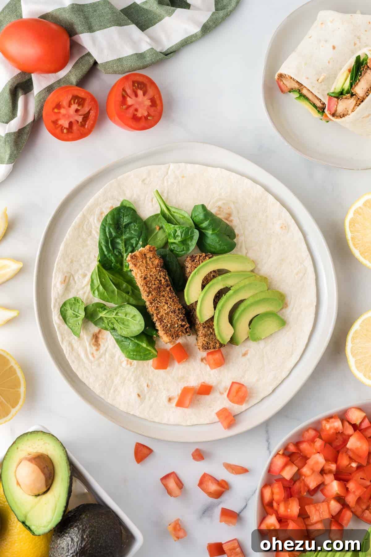 Vibrant Tofu Wraps 3 An open tofu wrap revealing layers of avocado, fresh spinach, juicy tomato slices, and crispy tofu, brightened with a squeeze of lemon.