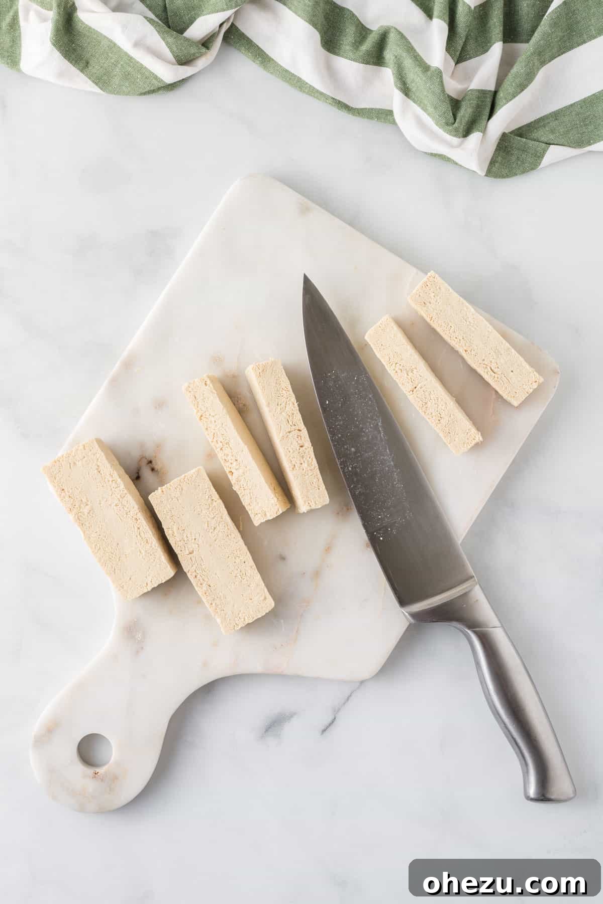 Vibrant Tofu Wraps 7 Hands demonstrating how to slice a block of pressed tofu into even strips on a cutting board.